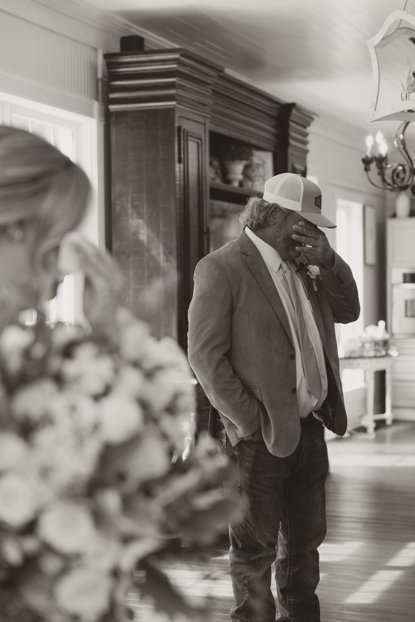 Black and white portrait of a suited man in a rustic indoor setting.