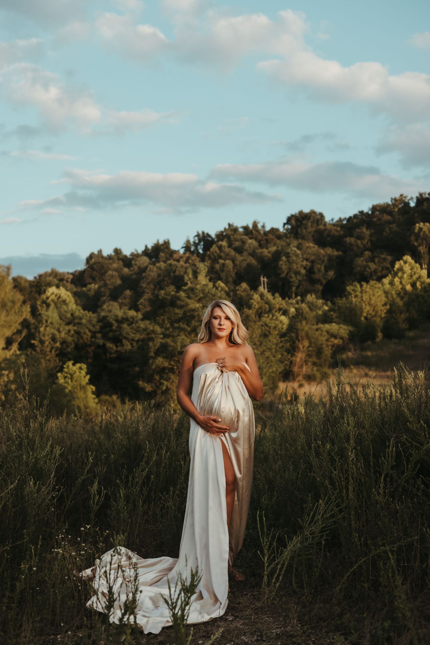White flowy dress photoshoot in a natural field setting with trees and blue sky.