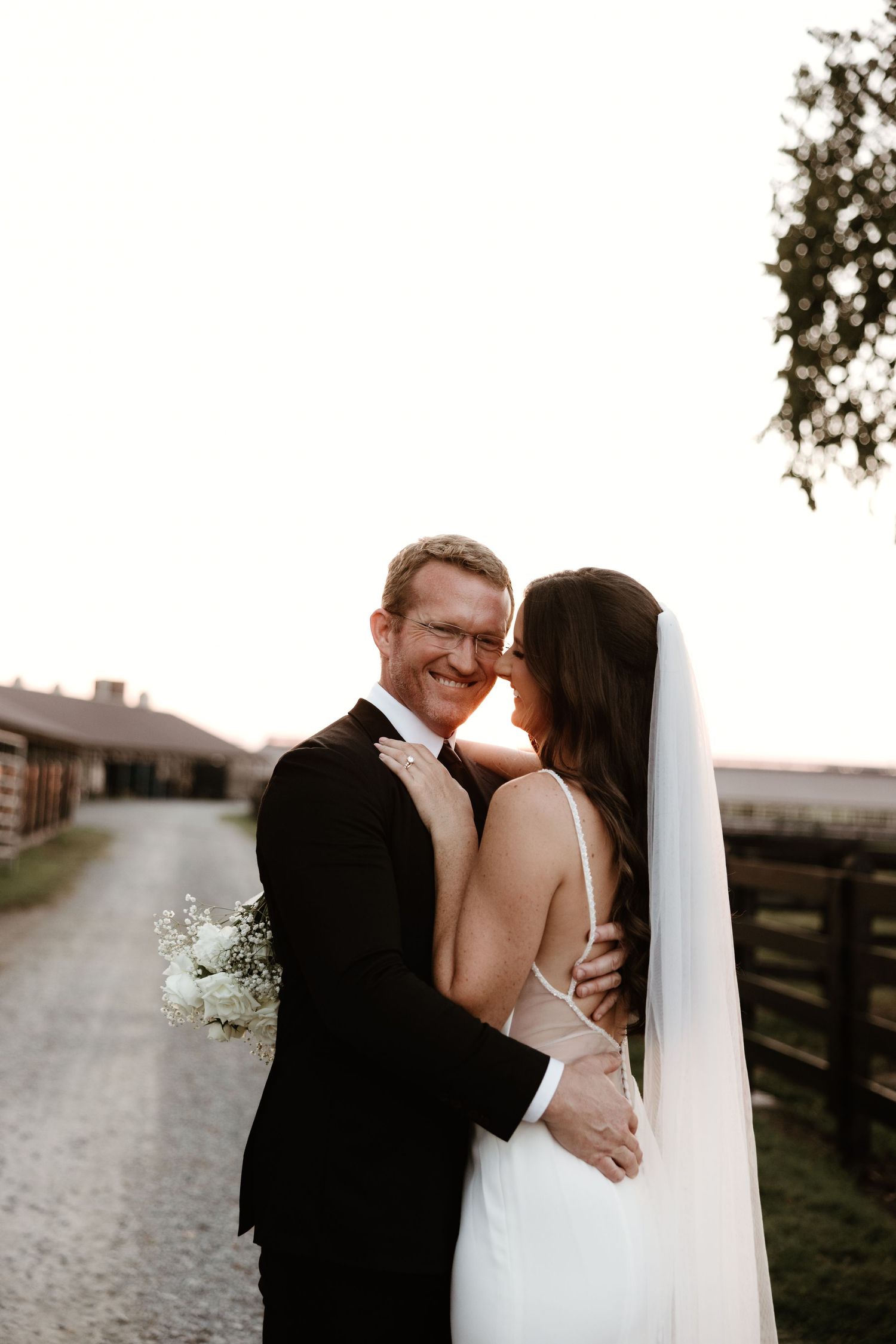 A romantic sunset wedding photoshoot shows the couple sharing intimate moments along a rustic fence line.