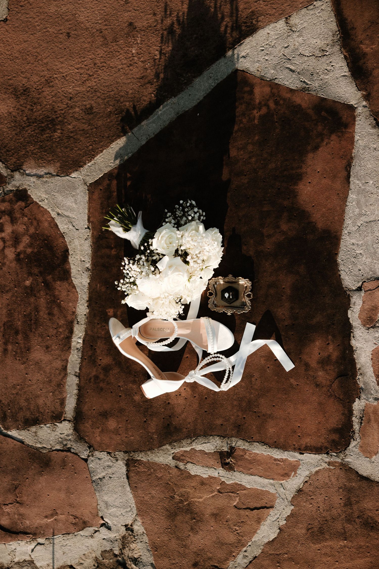White wedding decorations arranged against a textured brick wall in an artistic composition.