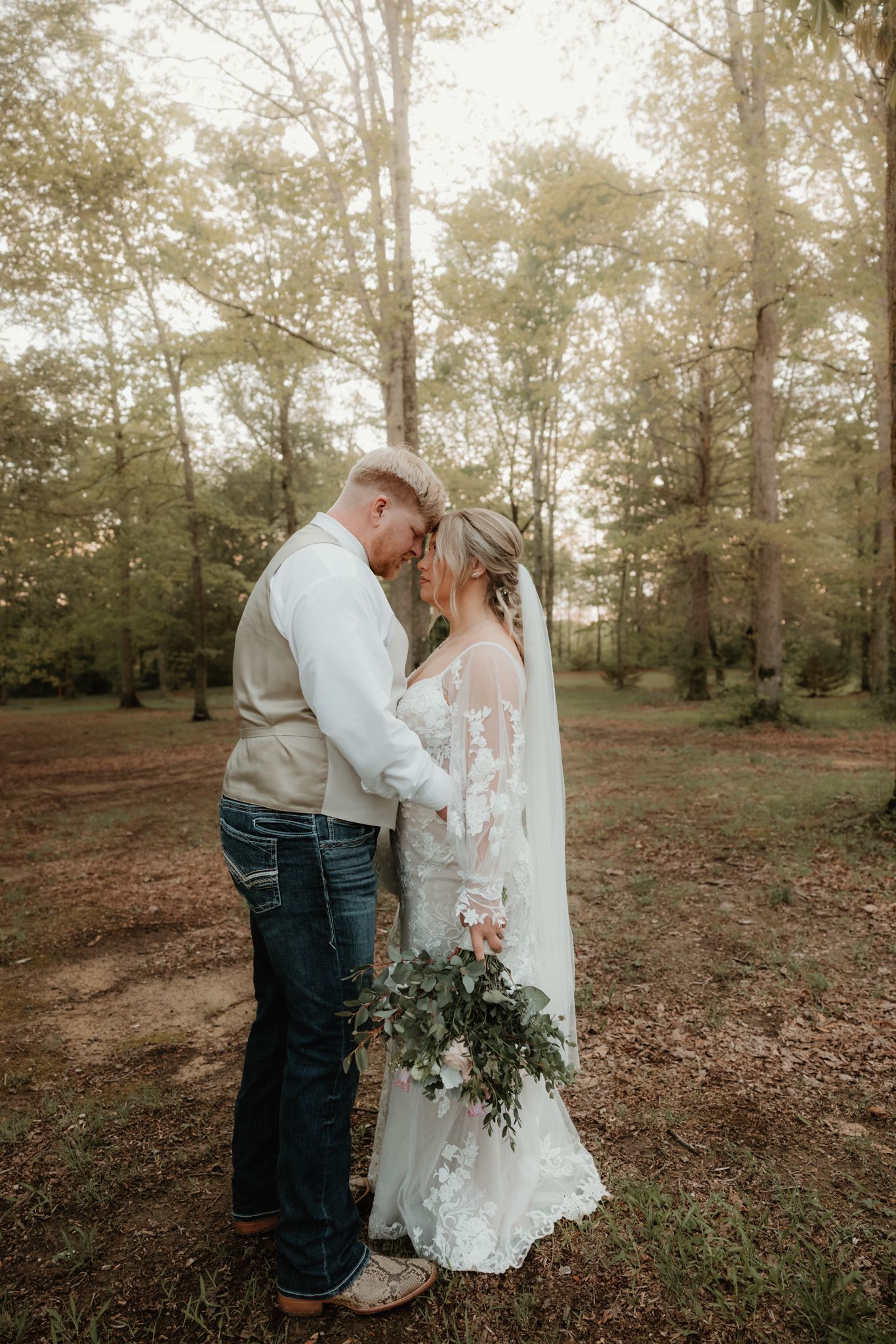 Couple shares romantic moment outdoors in a wooded setting during autumn wedding.