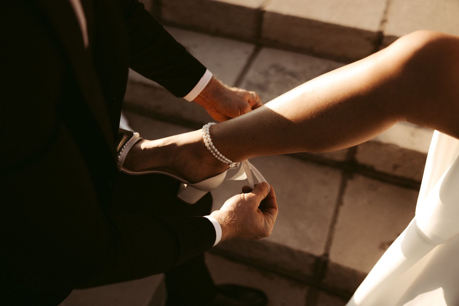 A hand reaches down holding a pair of sharp scissors cutting paper in a dark, dramatic lighting setting.