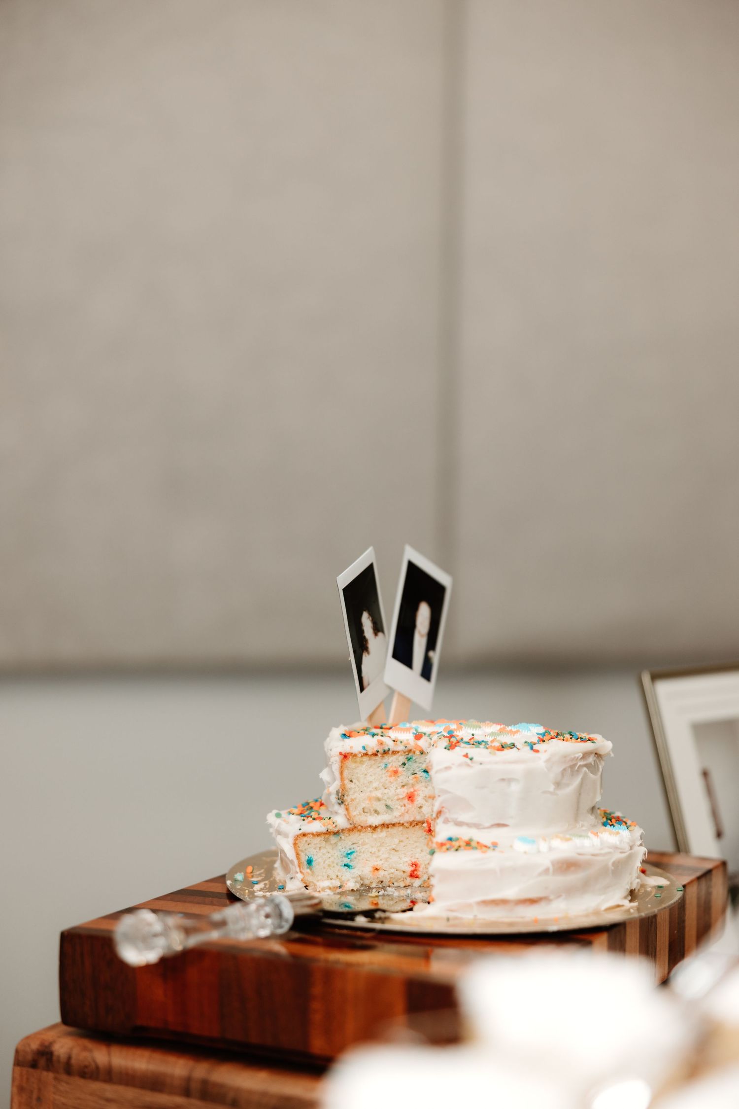 White frosted birthday cake with black bunny ears topper sits on wooden table surface.