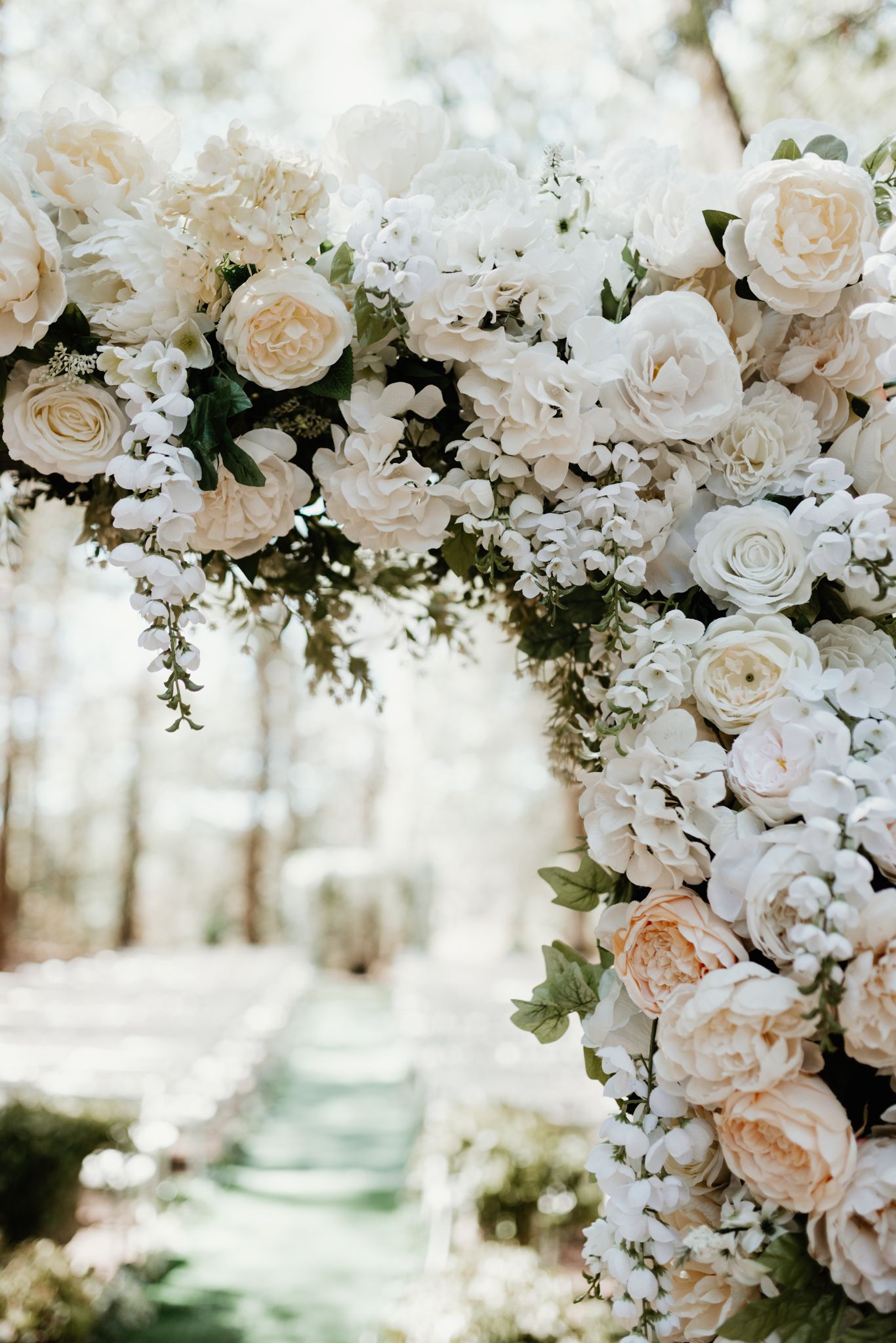 Elegant white rose and hydrangea floral arch arrangement for wedding ceremony.