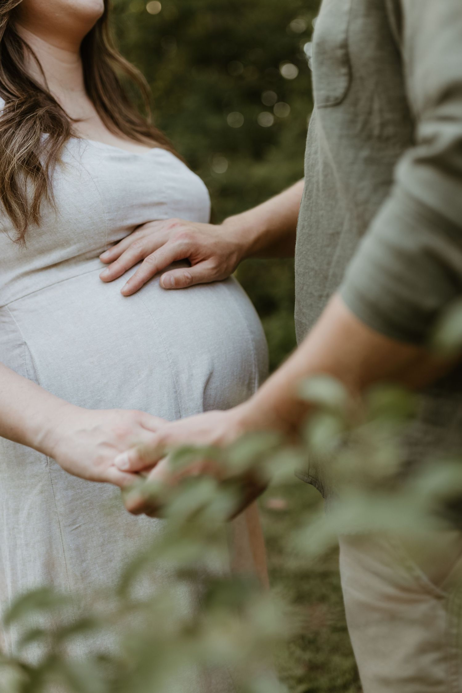 Close-up shot focusing on hands tenderly cradling a pregnant belly.