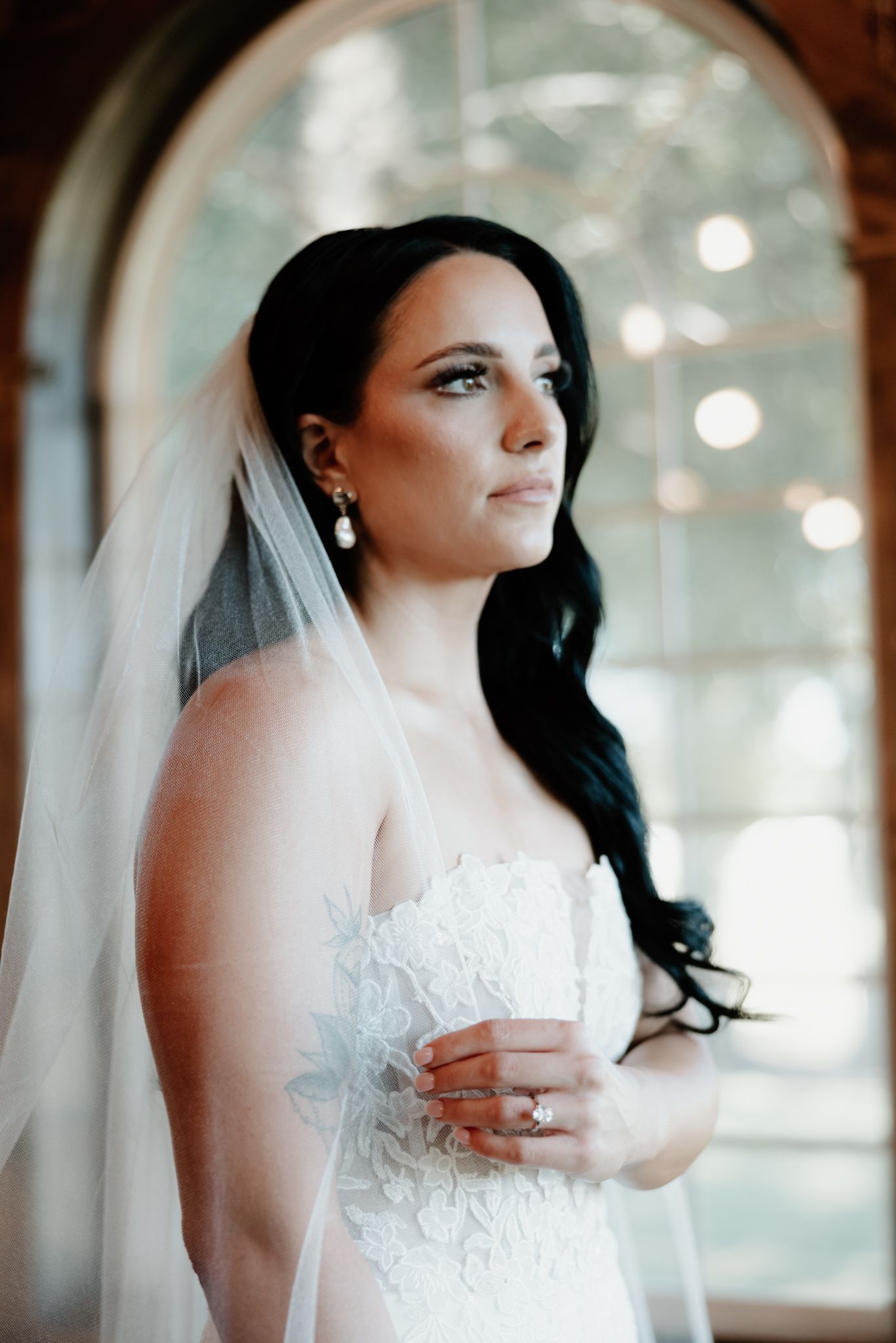 Dreamy bridal portraits showing close-up details of a white lace wedding dress and flowing veil.