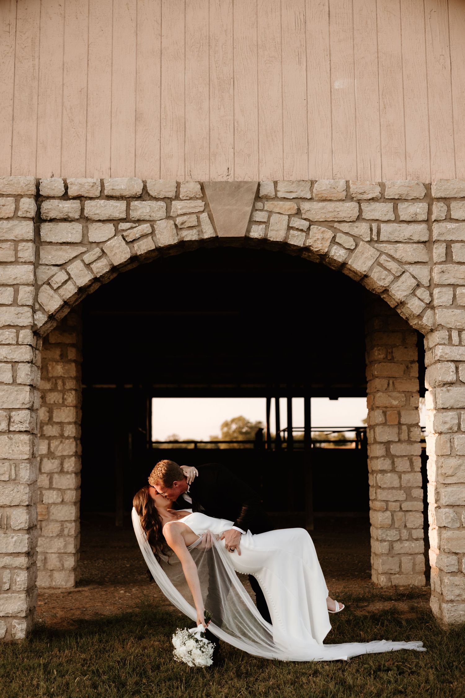 Someone in a white gown poses dramatically in a series of arched stone doorways for artistic photos.