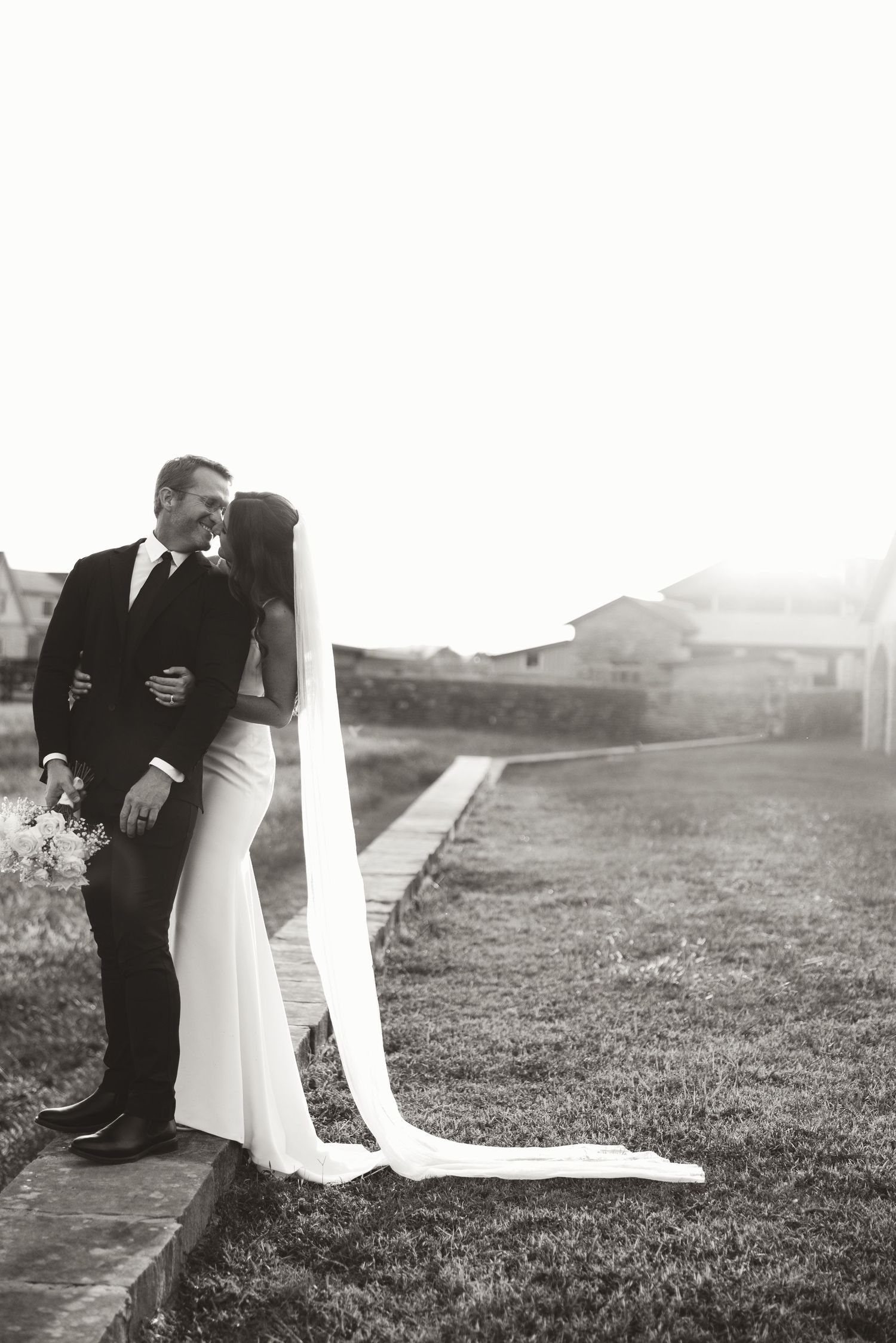 Black and white artistic wedding photos showing intimate moments on a grassy field.