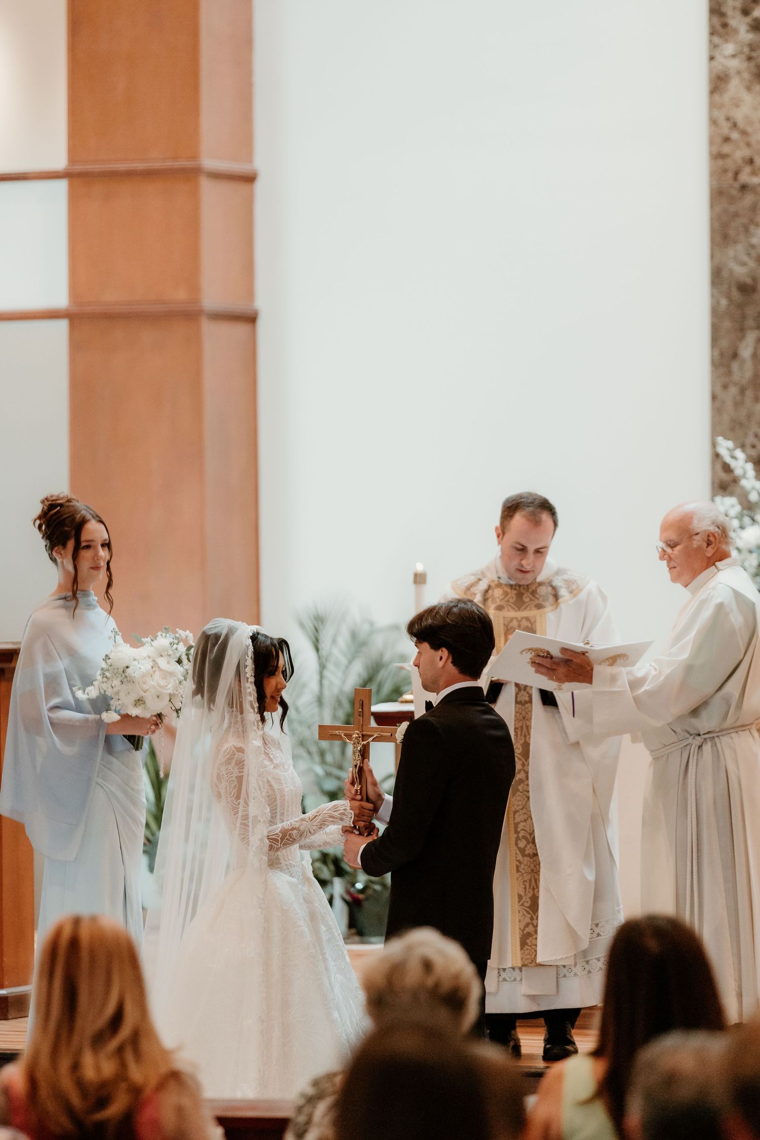 Bride and groom exchange vows at a church altar with priests officiating during a traditional wedding ceremony.