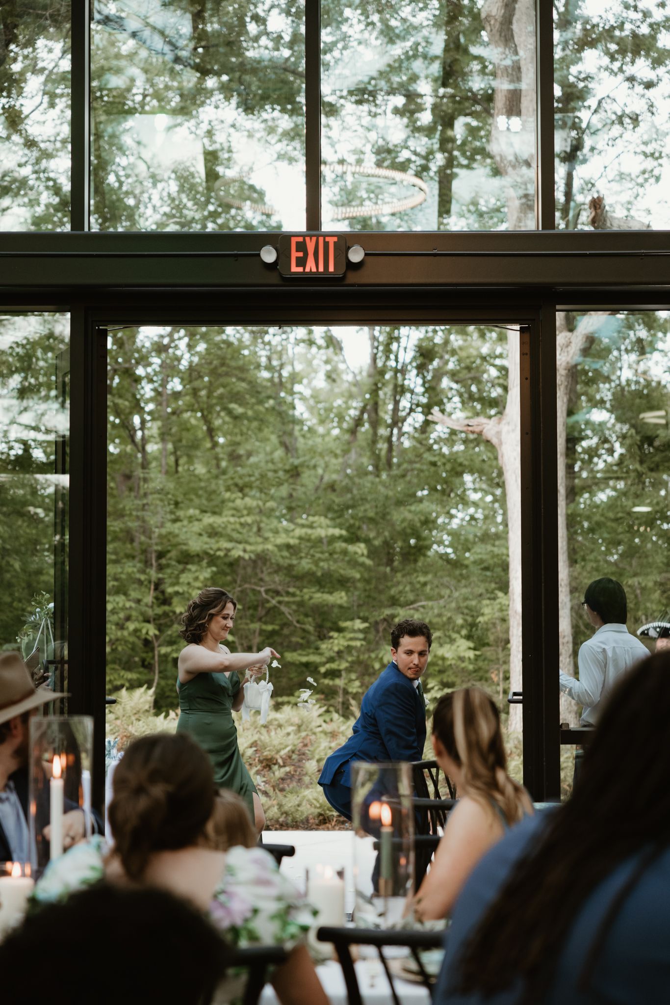 Wedding reception venue interior with large windows overlooking wooded scenery.