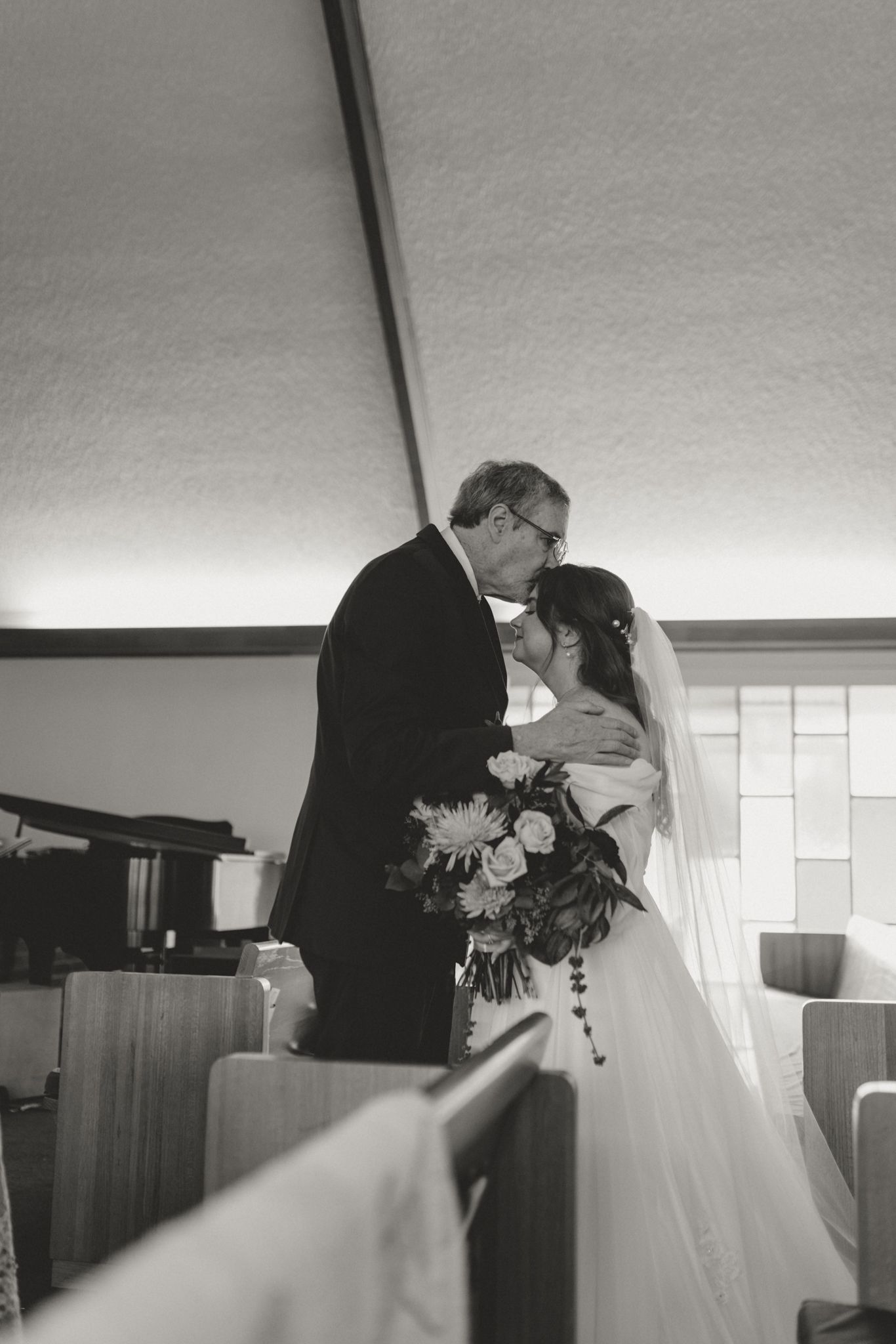A black and white wedding photograph taken inside a church during the ceremony.