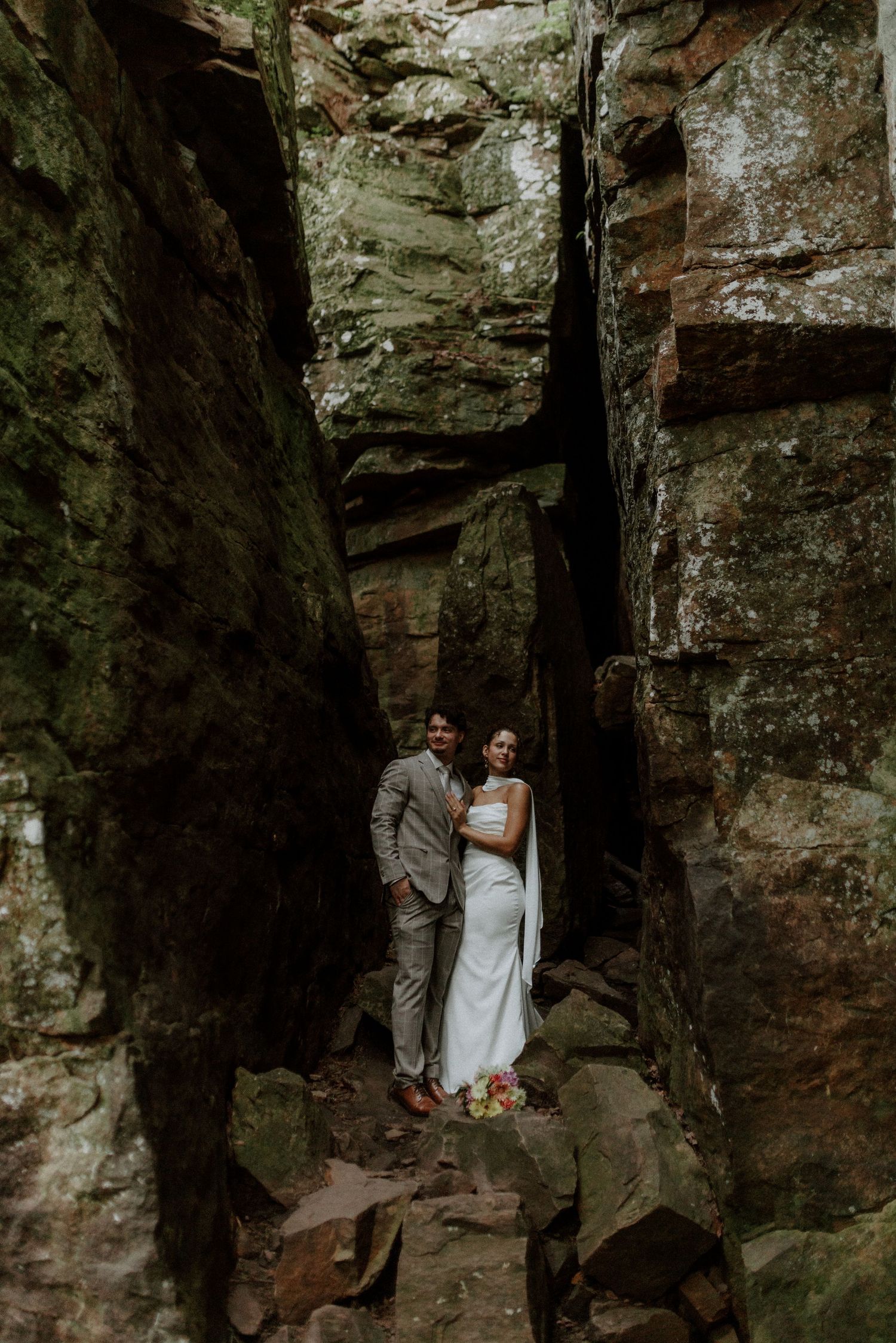Bride and groom pose romantically between towering rock formations during their adventurous elopement.