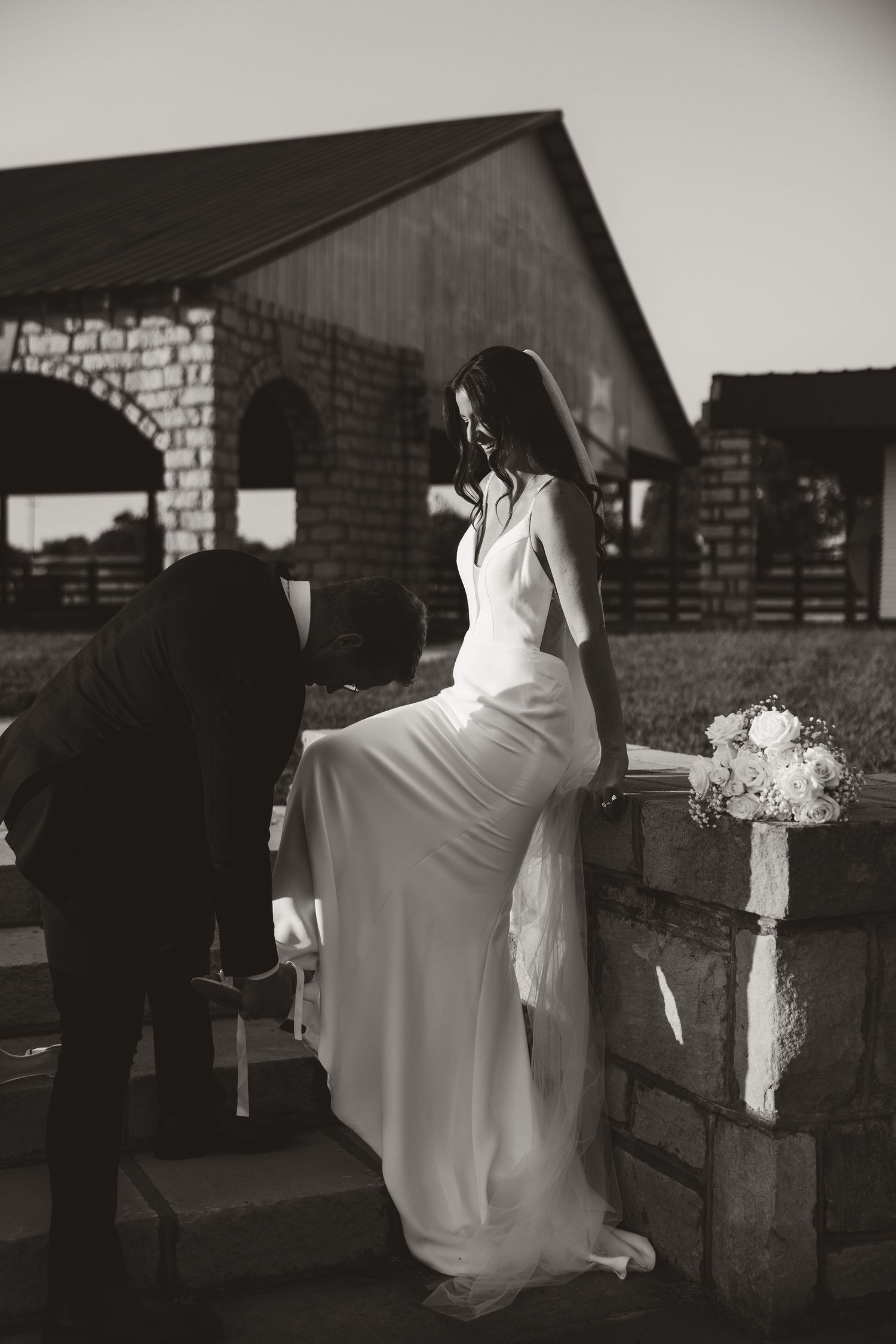 Black and white wedding photos showing tender moments between a couple against a brick wall.