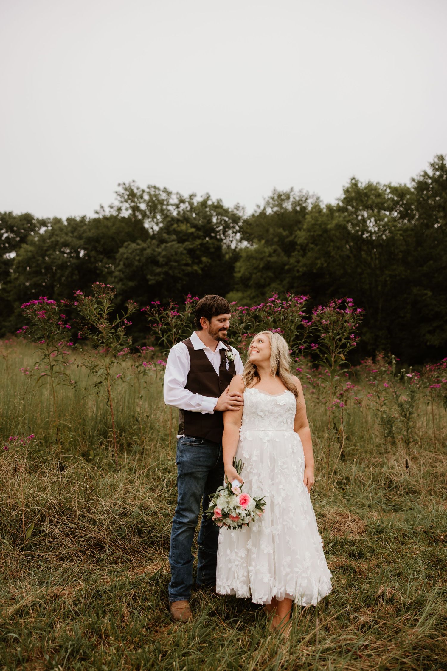 Couple shares romantic moments in a wildflower field during rustic outdoor wedding photo session.