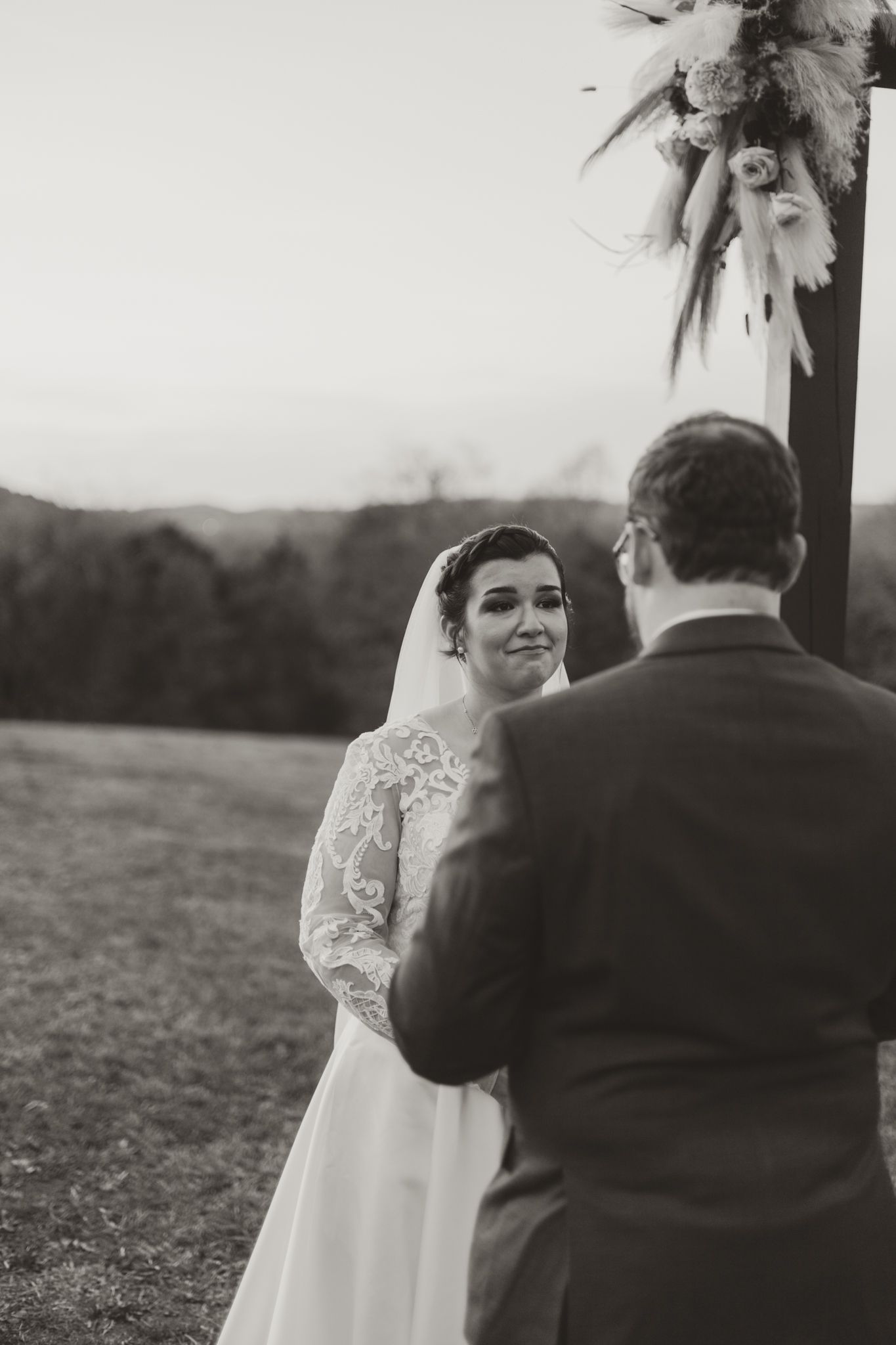 A heartfelt moment between newlyweds at an outdoor wedding ceremony with palm tree decor and natural scenery.
