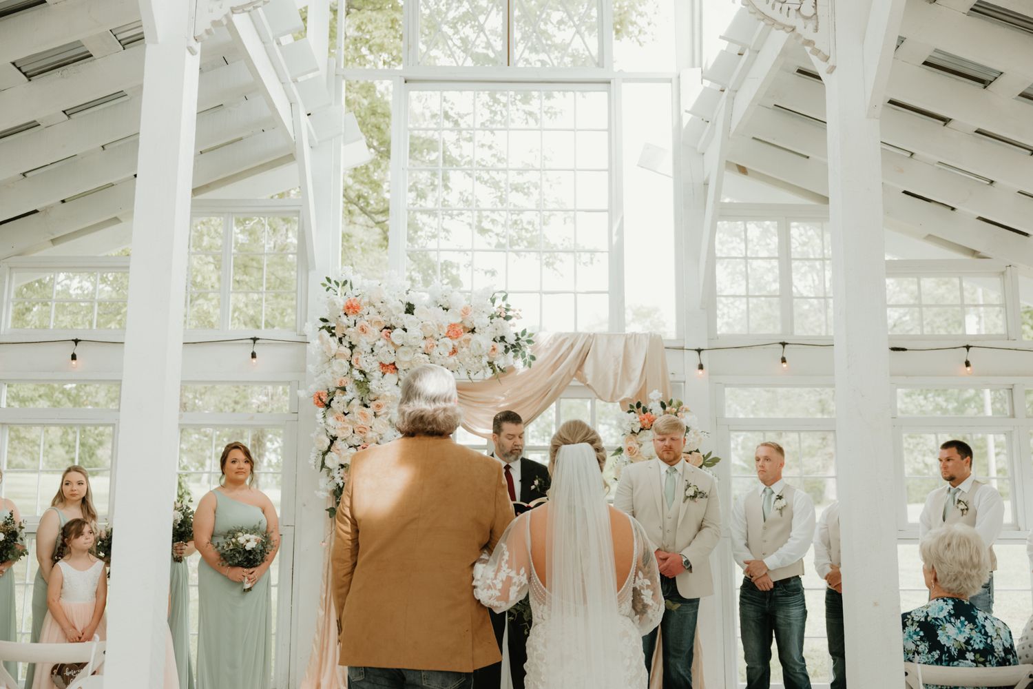 Wedding celebration in a bright white chapel with floral décor and chandelier.