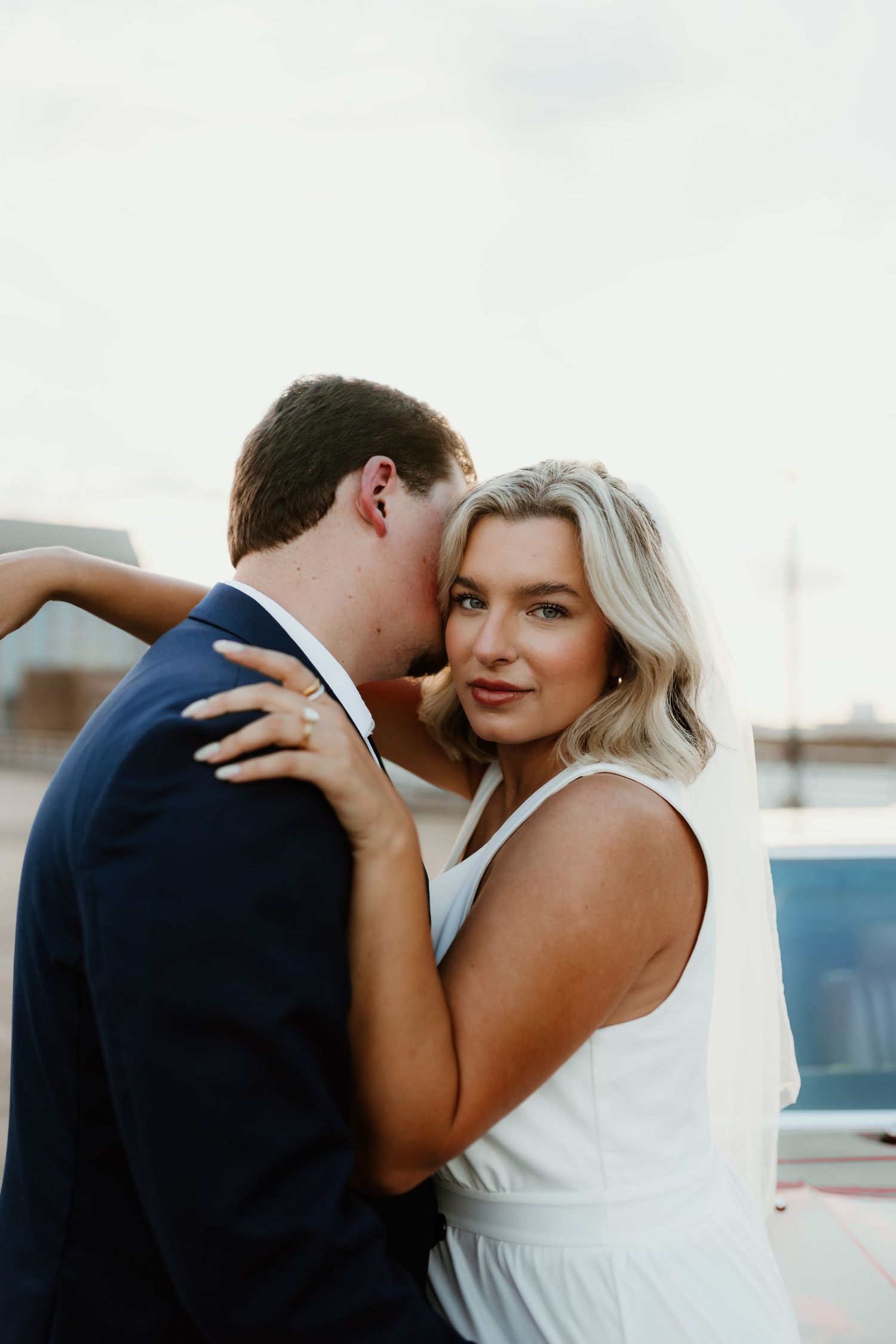 Intimate moment between newlyweds embracing outdoors on their wedding day.