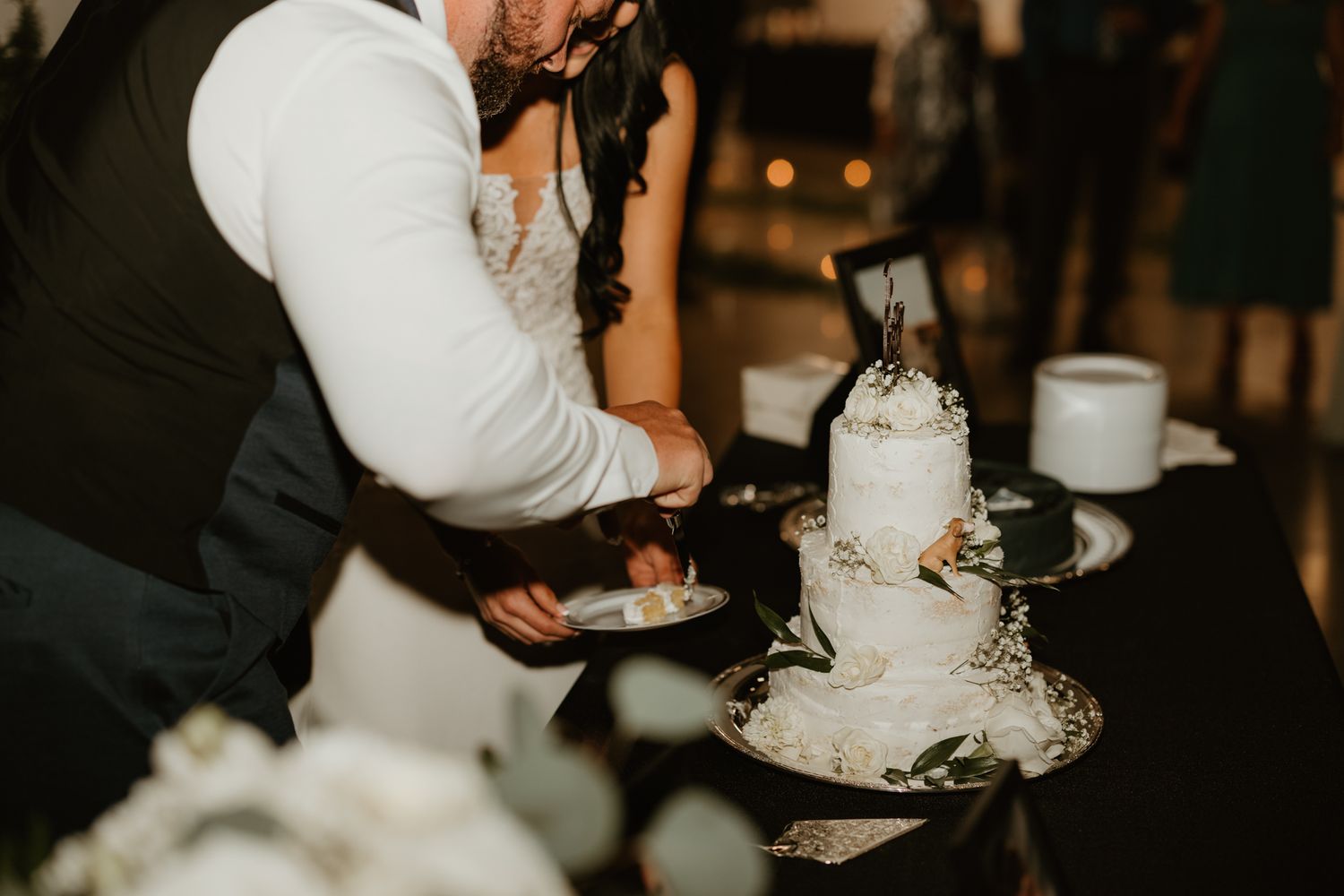 Wedding cake cutting sequence in dimly lit reception venue with decorative details.