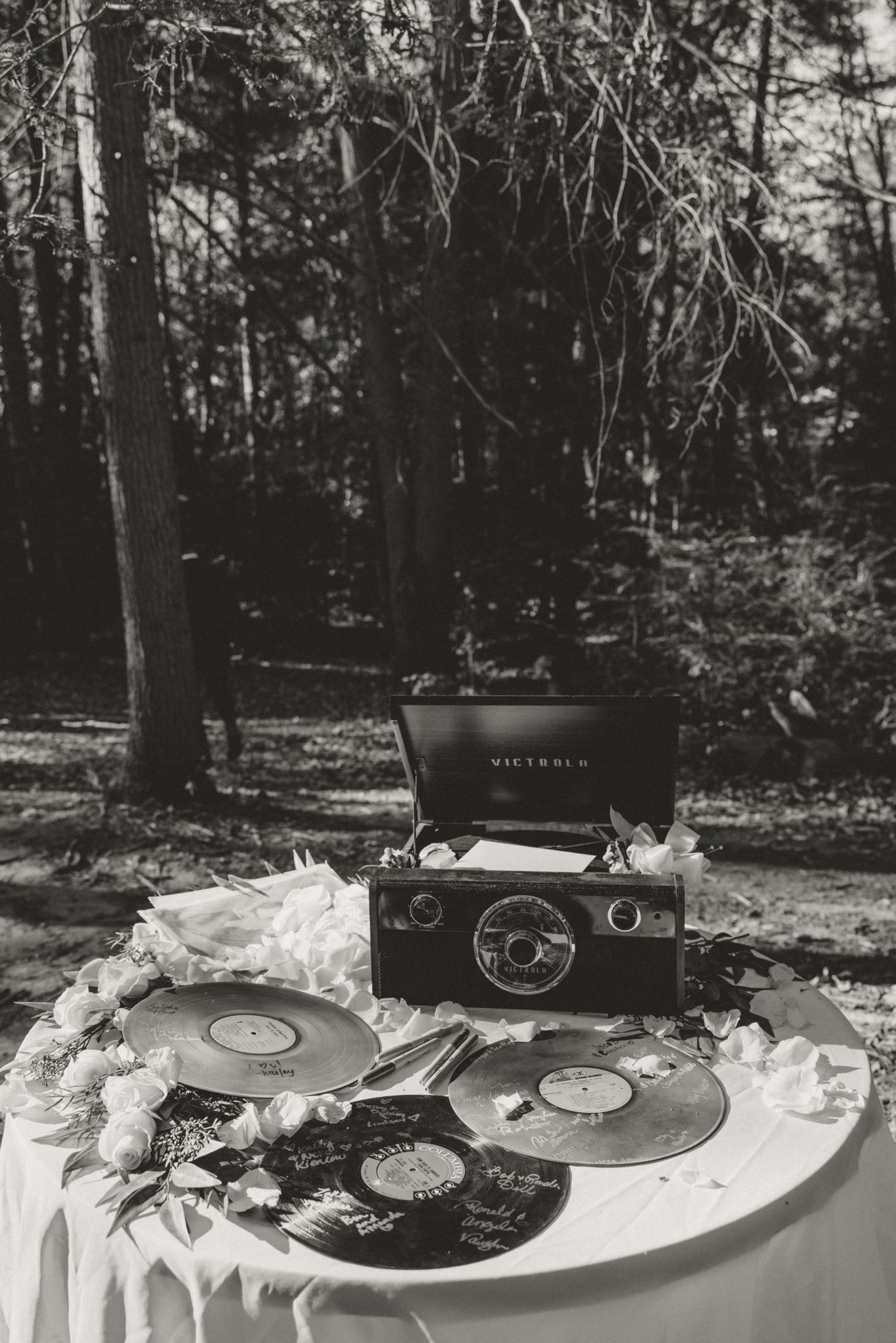 Vintage record players and vinyl records arranged on a white tablecloth at an outdoor event.