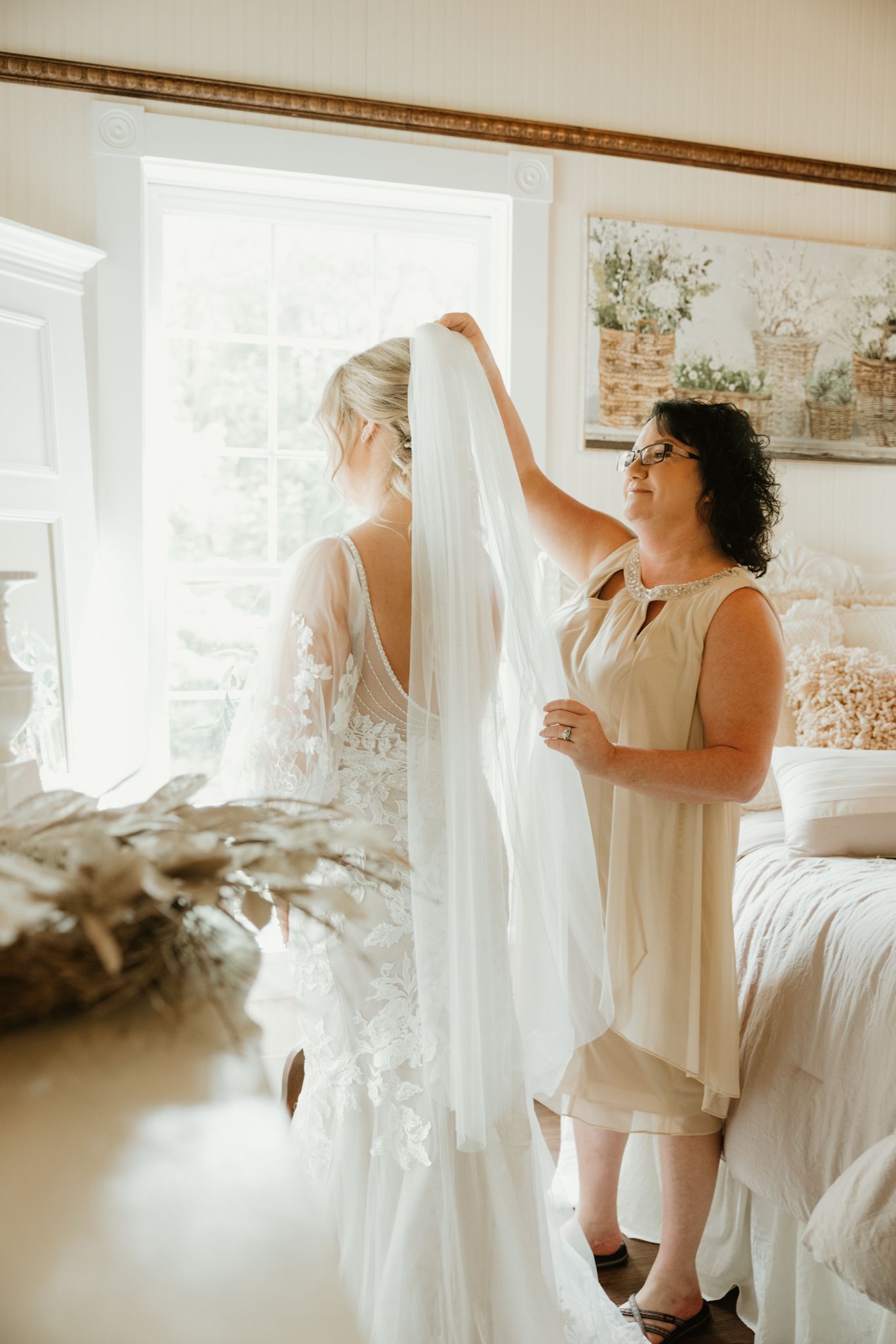 Wedding dress being prepared in sunlit bridal suite with lace details.