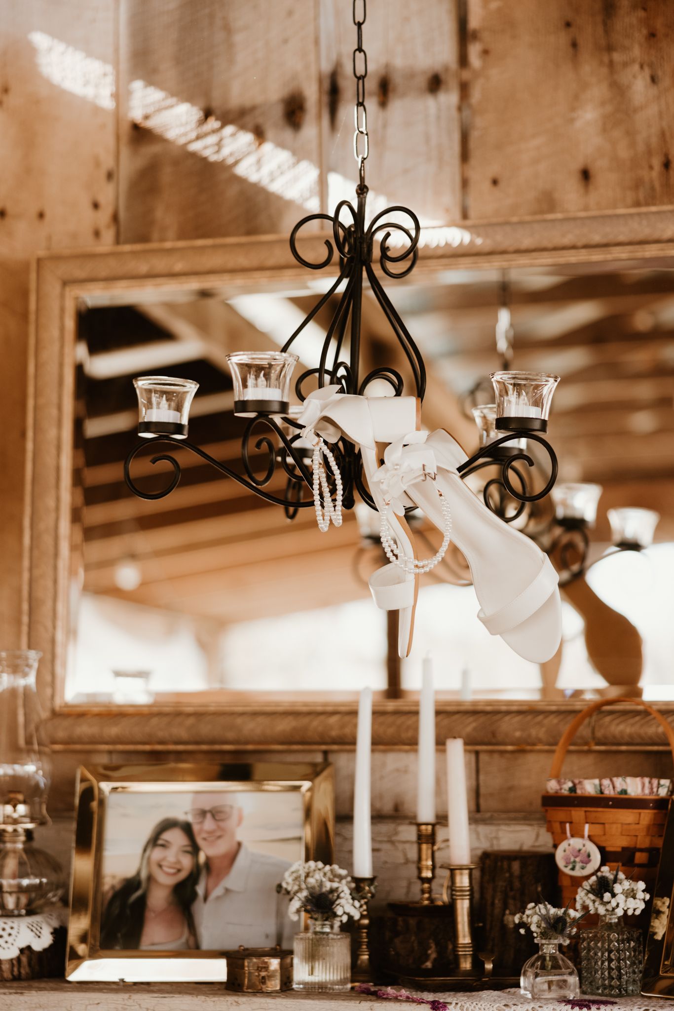 Decorative iron chandelier and wedding decor in a rustic wooden interior setting.