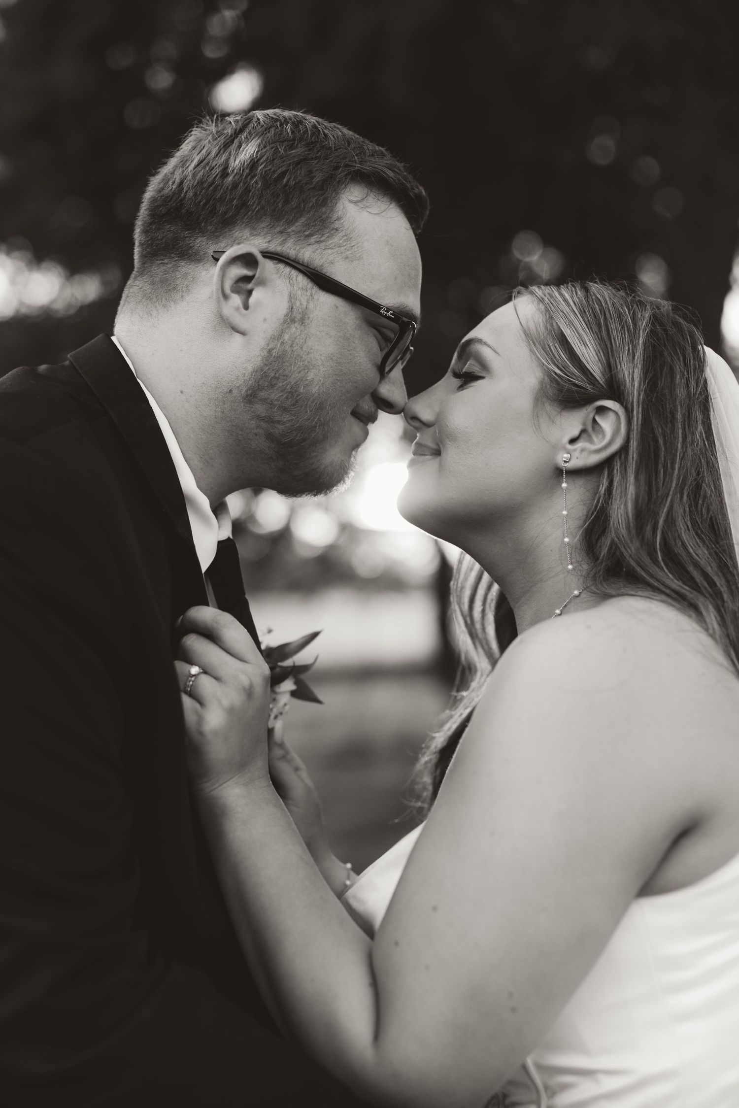 A romantic black and white wedding photo capturing a tender moment between newlyweds sharing an intimate kiss.