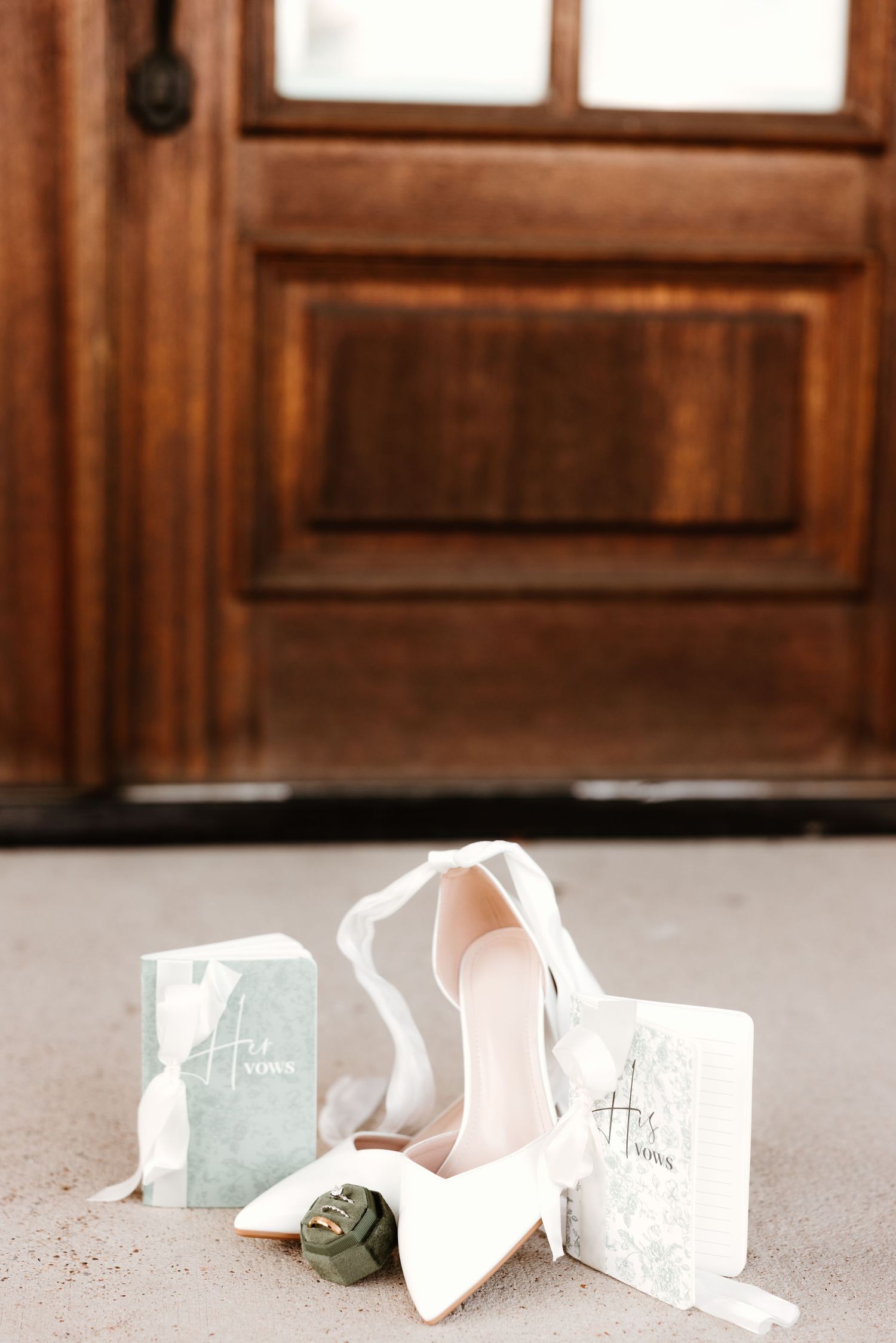 A series of white ballet or wedding shoes laid out in a row on a carpeted floor next to small blue boxes.