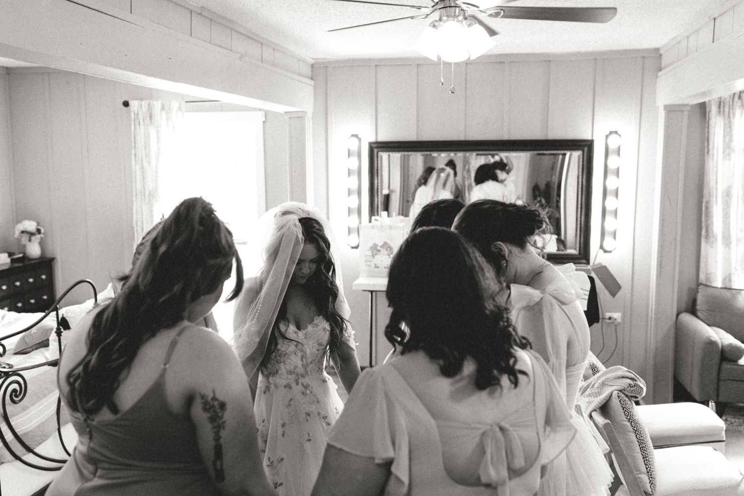 Black and white panoramic image showing wedding day preparations in a bright interior hallway.