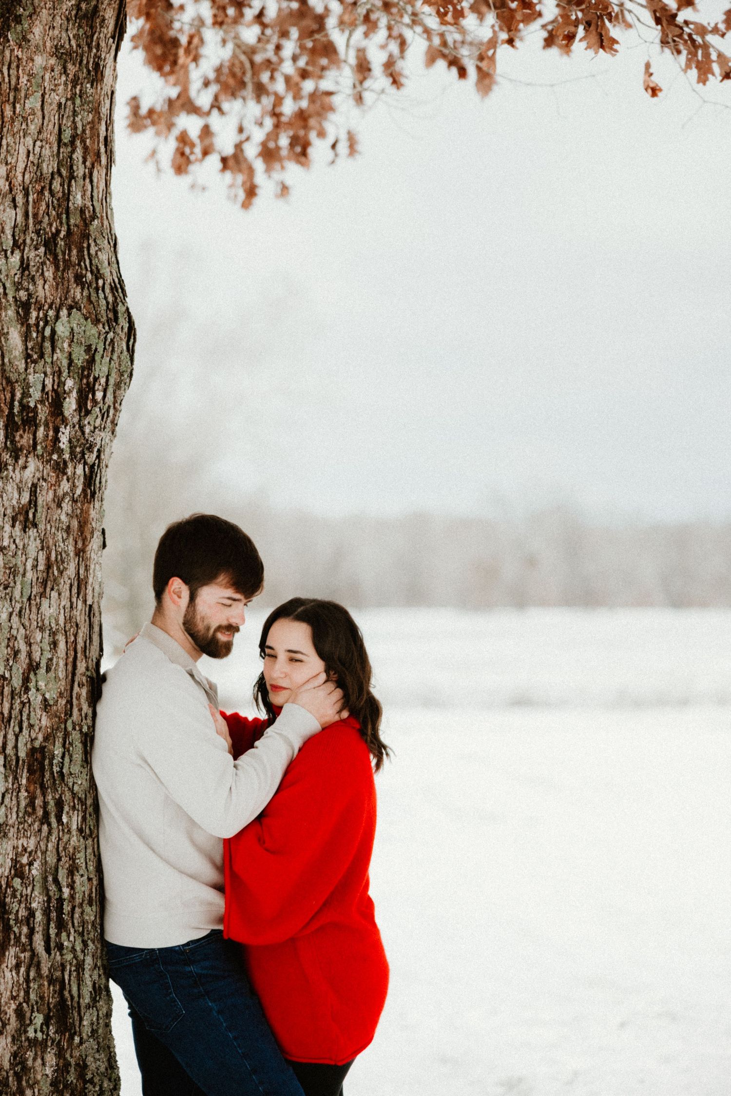 Winter engagement photos of a couple in red and white against snowy backdrop.