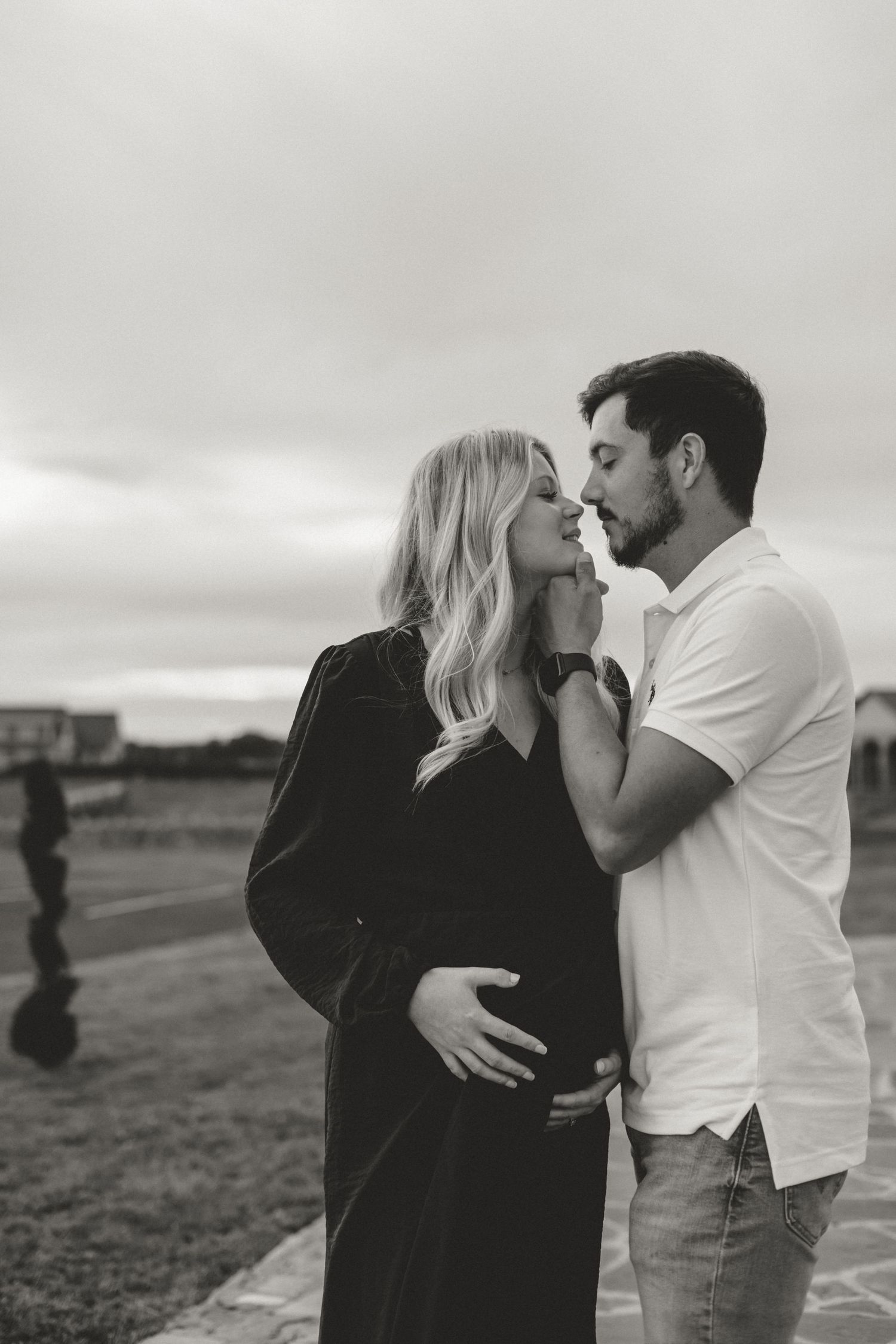 An intimate black and white portrait of an expectant couple sharing a tender moment.