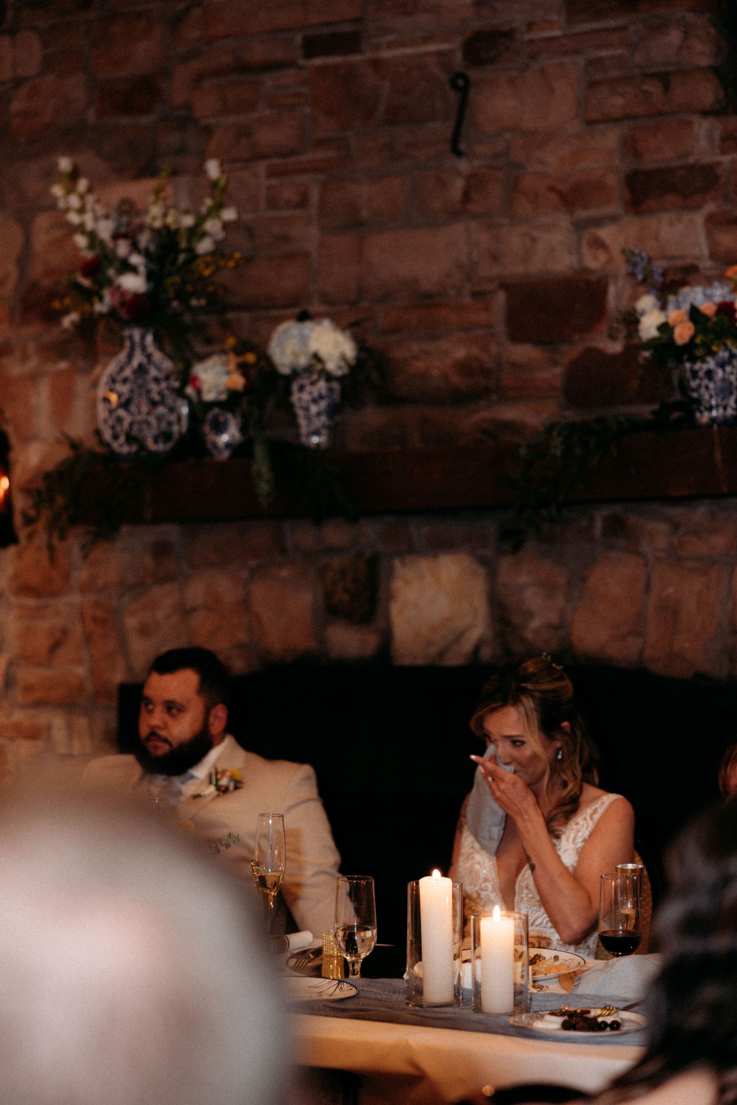 Wedding reception dinner in rustic brick venue with candlelight and floral decorations.