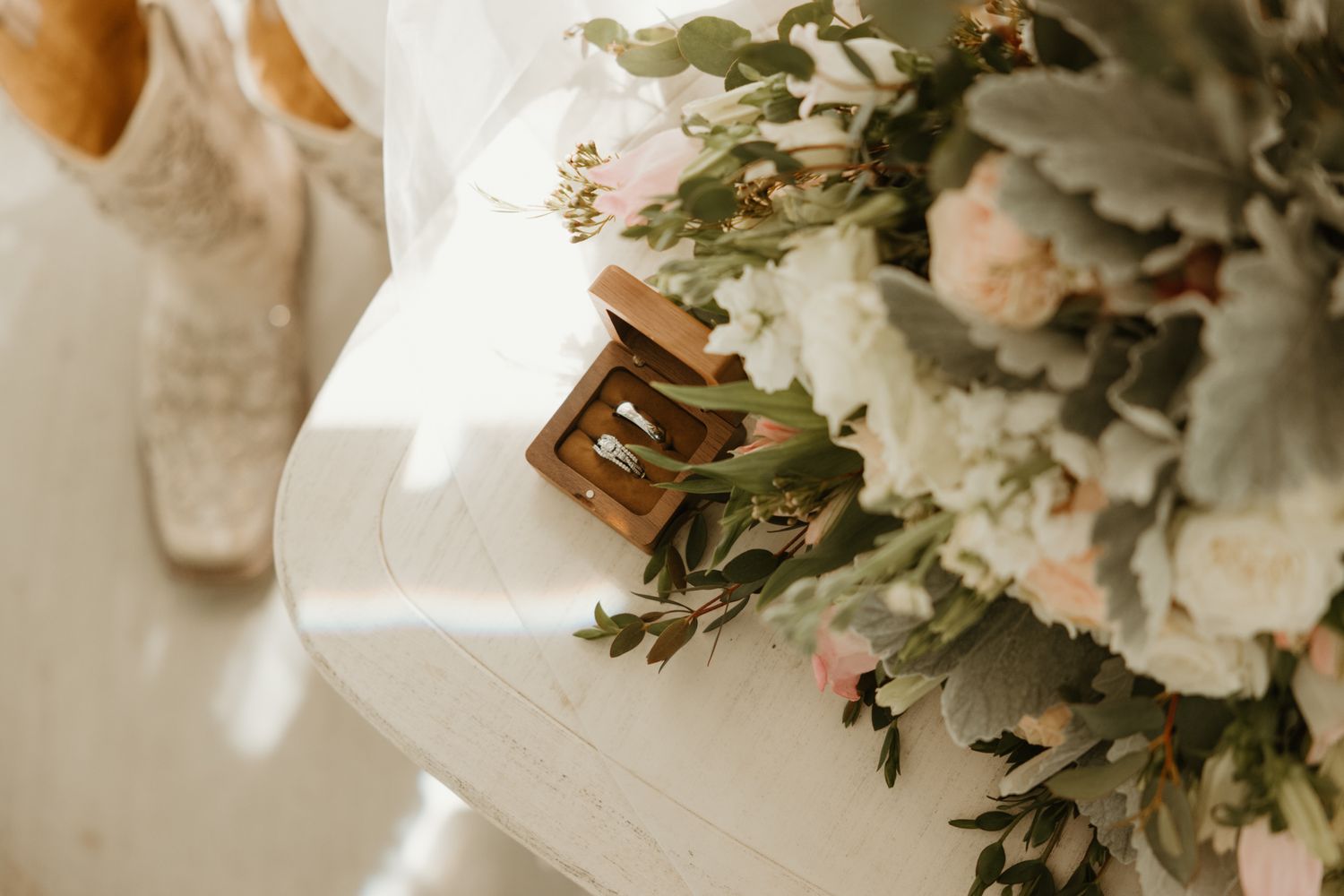 Close-up detail of a floral bouquet with white roses and greenery against a soft, ethereal backdrop.