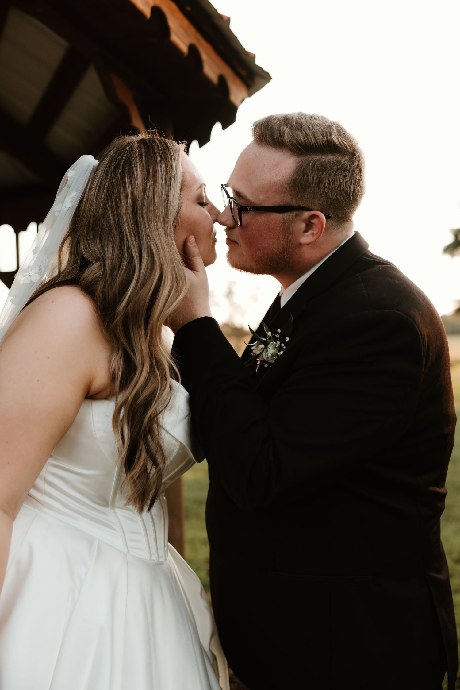 Romantic black and white wedding portraits of couple kissing at sunset in silhouette style composition.