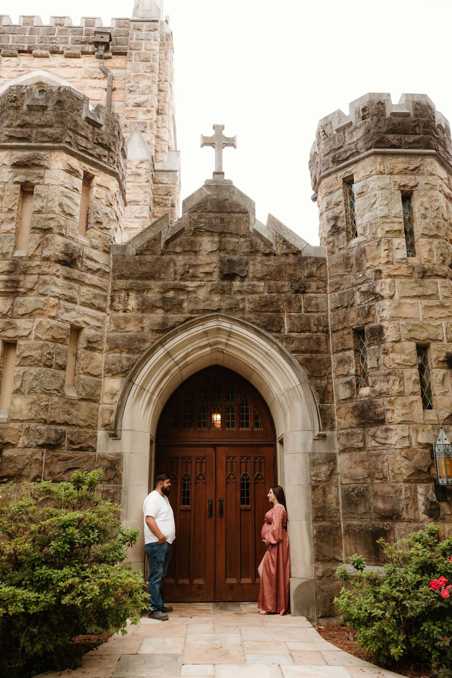 Gothic stone church entrance with a couple standing beneath an ornate arched doorway.