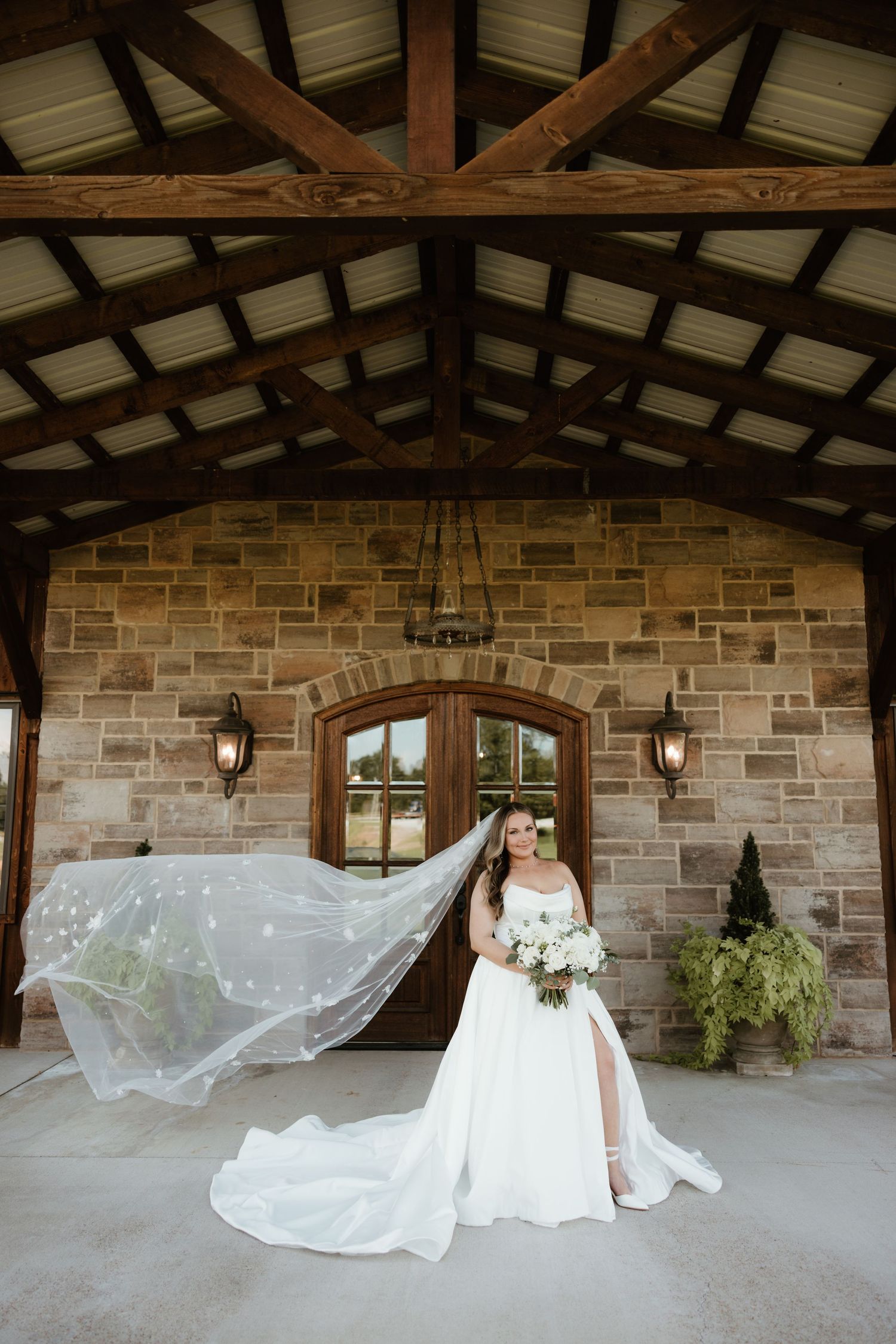 Beautiful wedding venue entrance with exposed wooden beams, stone walls and a flowing white veil catching the breeze.