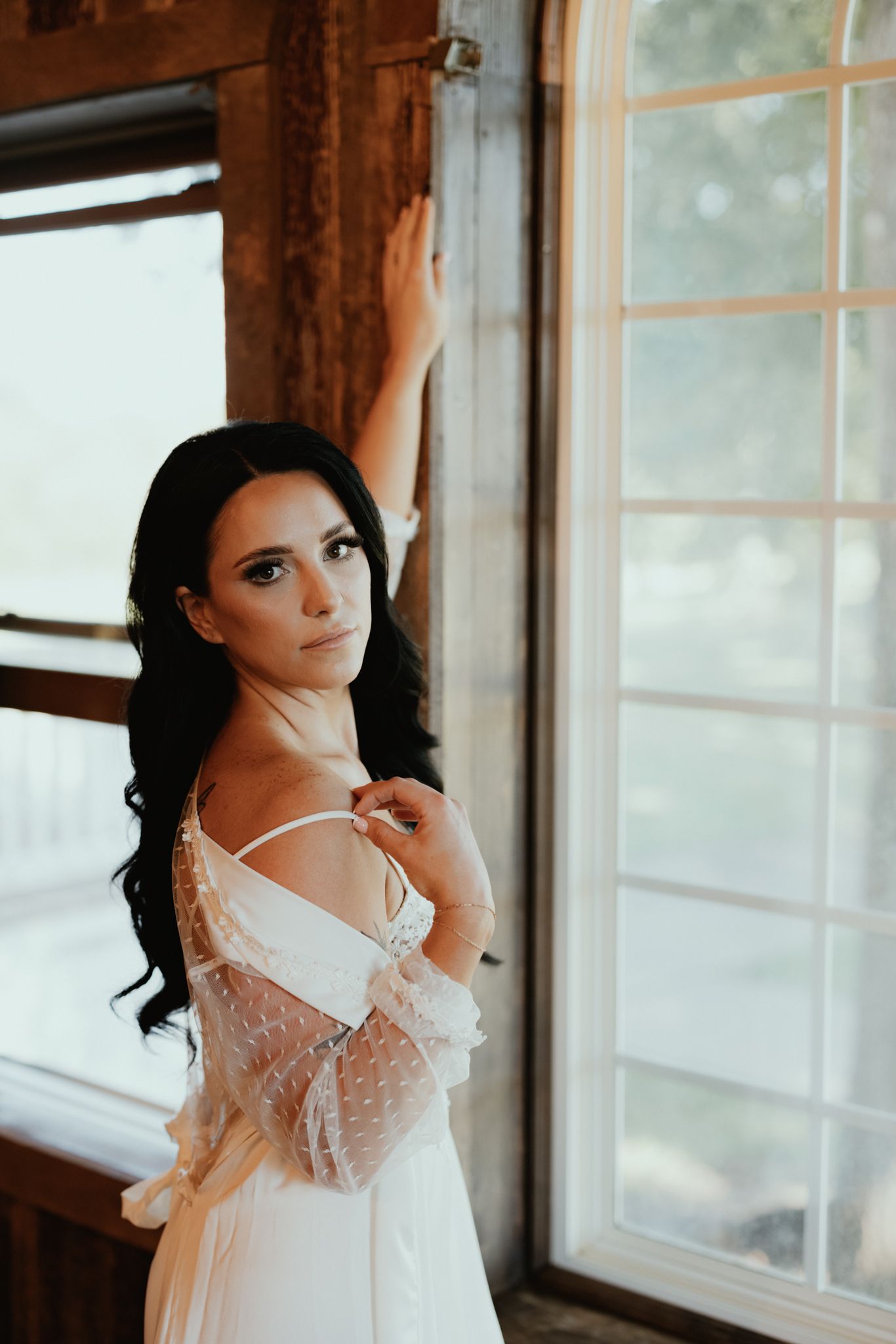 Elegant white lace boudoir robe photographed against a bright window in romantic lighting.