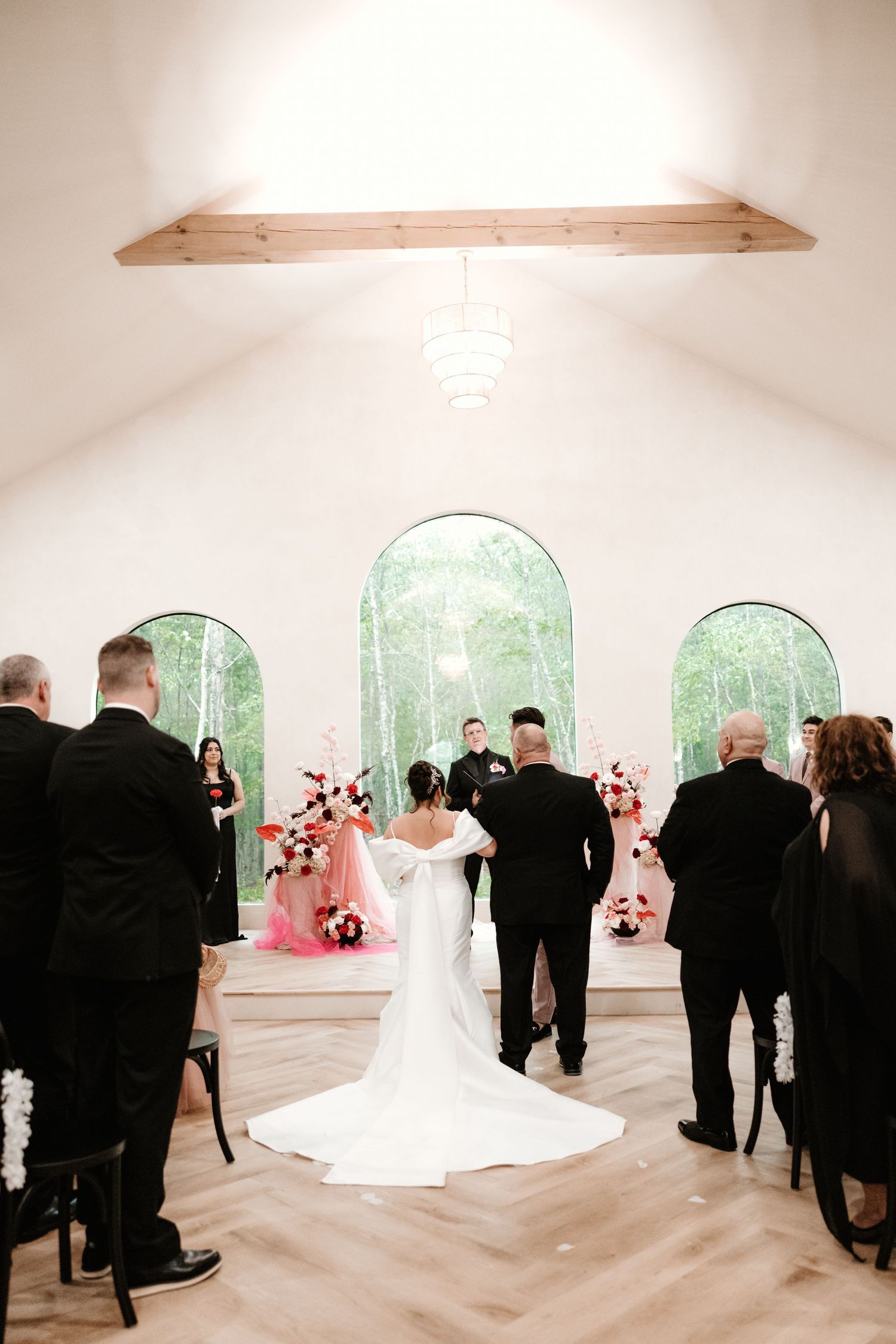 Wedding ceremony in modern chapel with arched windows and wooden beam ceiling.