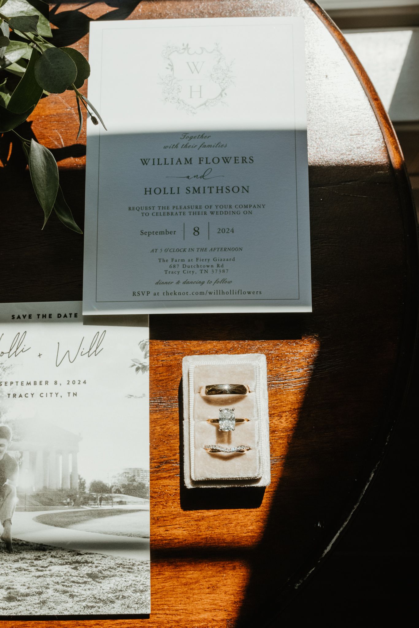 Wedding invitation suite with gray cards and gold rings displayed on a wooden surface.