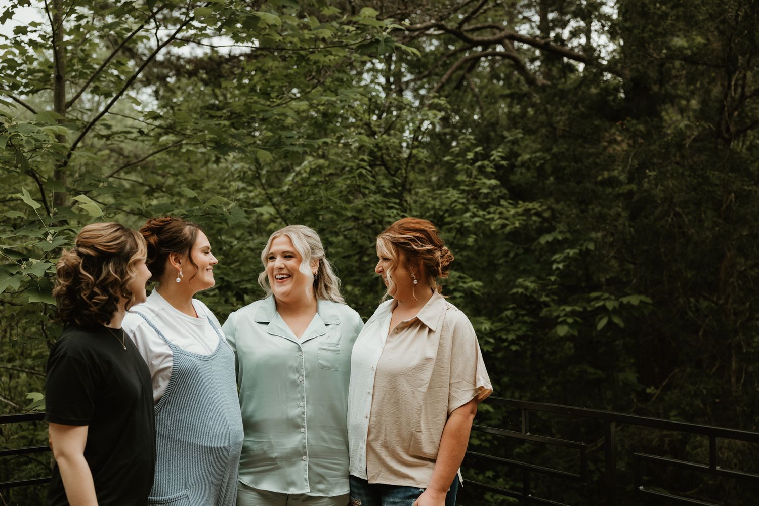 A group stands together outdoors sharing a candid moment against a lush green forest backdrop.
