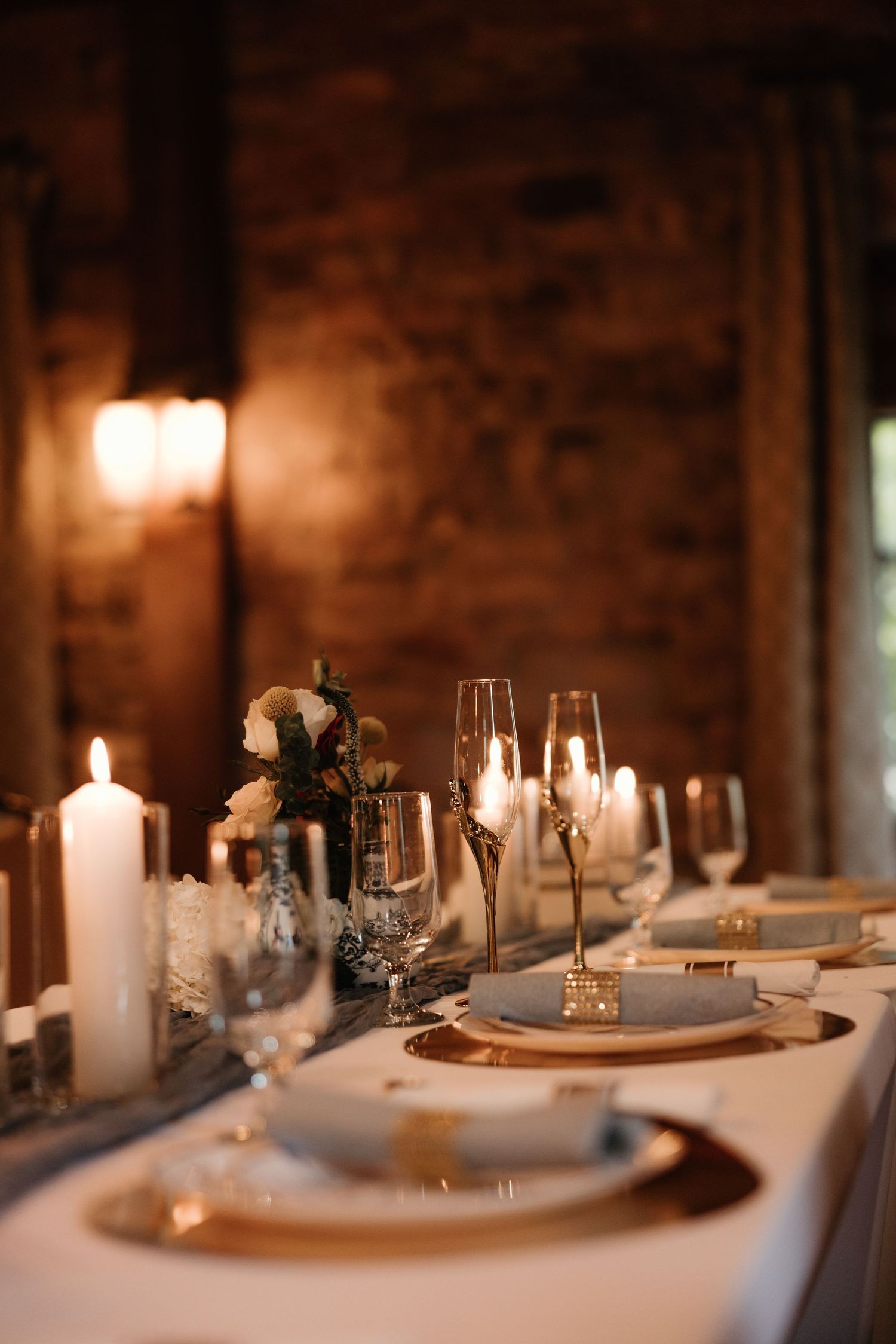 Elegant table setting with lit candles, wine glasses and white plates in a romantic ambiance.
