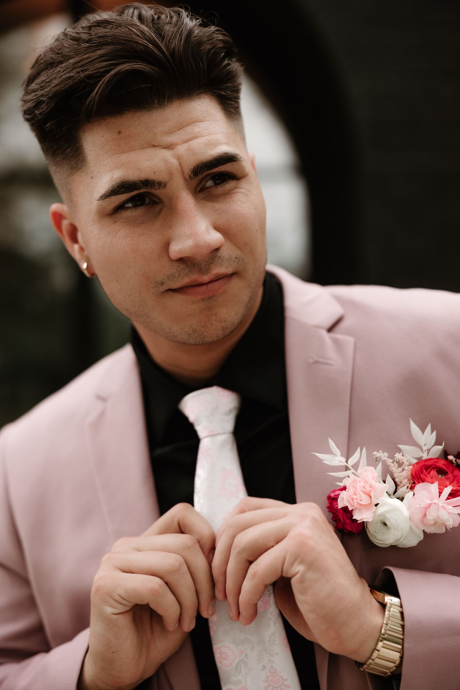 Groom in pink suit jacket with floral boutonniere and white dress shirt.