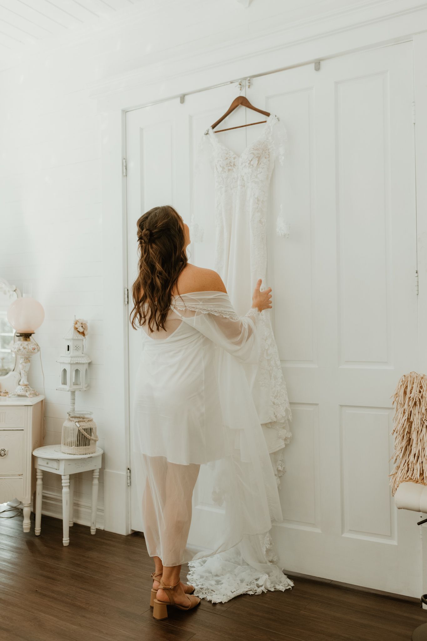 A sequence of four images shows someone in a white dress hanging it up on display in a bright white room interior.