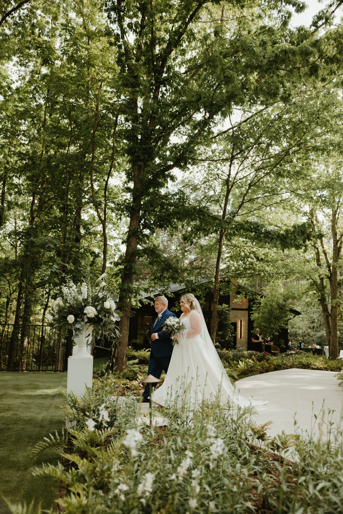 Beautiful outdoor garden setting with white floral arrangements and natural greenery.