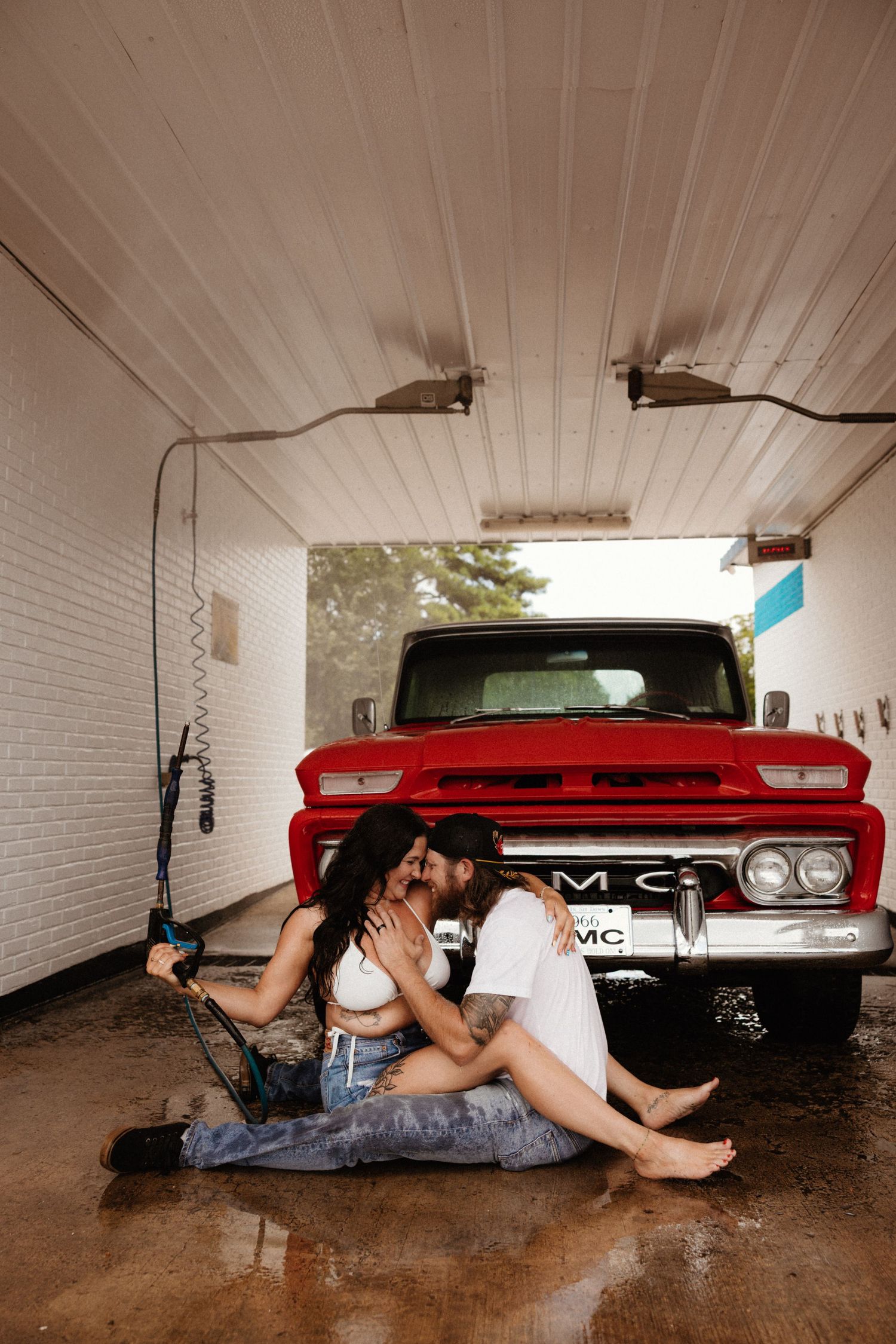 A romantic moment shared in front of a vintage red GMC truck in a white-walled garage.