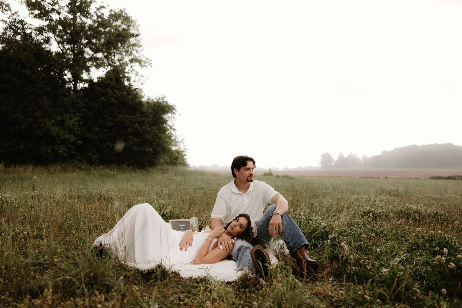 Couple relaxes on blanket in wildflower meadow during sunset.
