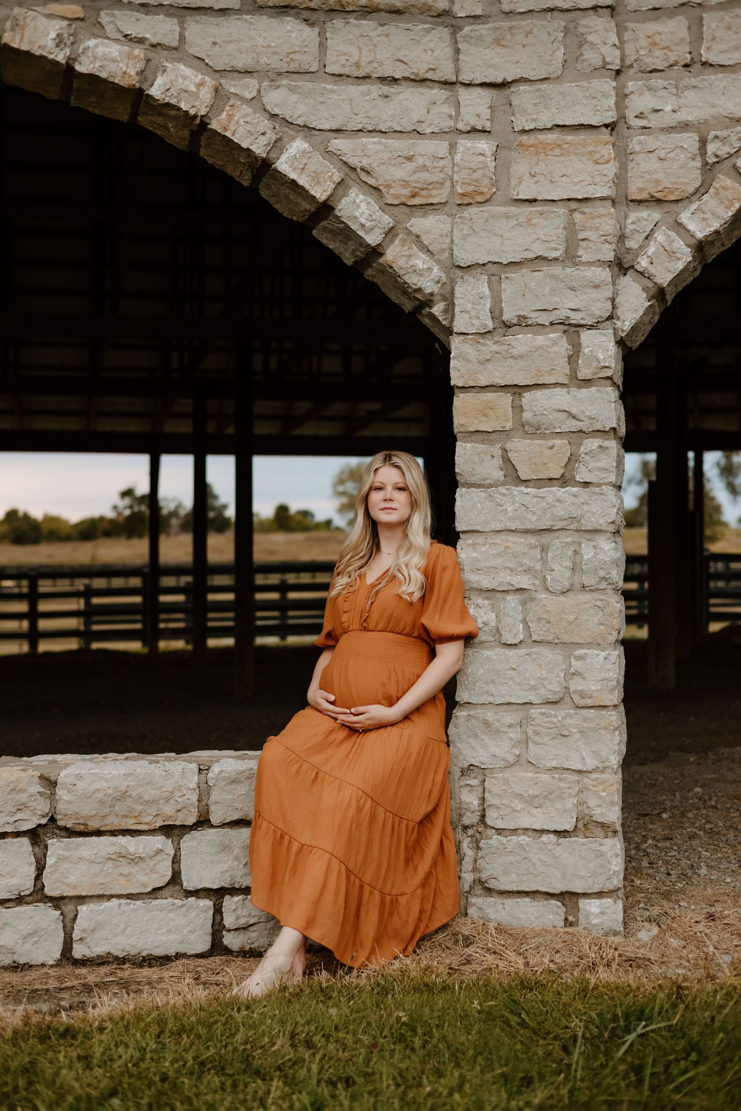 A series of portrait shots against a stone archway featuring a person in a flowing burnt orange dress sitting and posing.