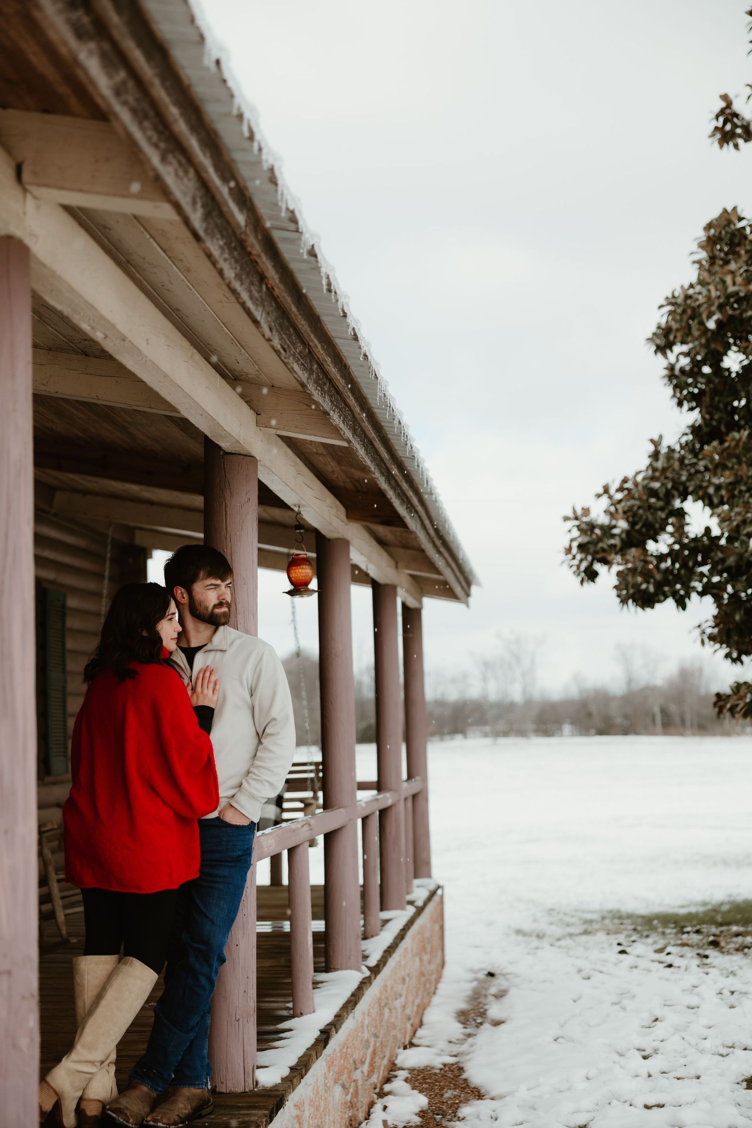 Winter engagement session at a snow-covered pavilion with architectural columns.
