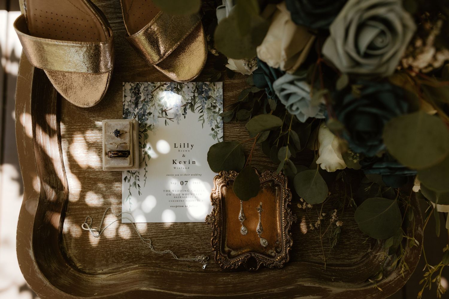 A perfume bottle and floral arrangement cast dappled sunlight shadows on an antique tray.