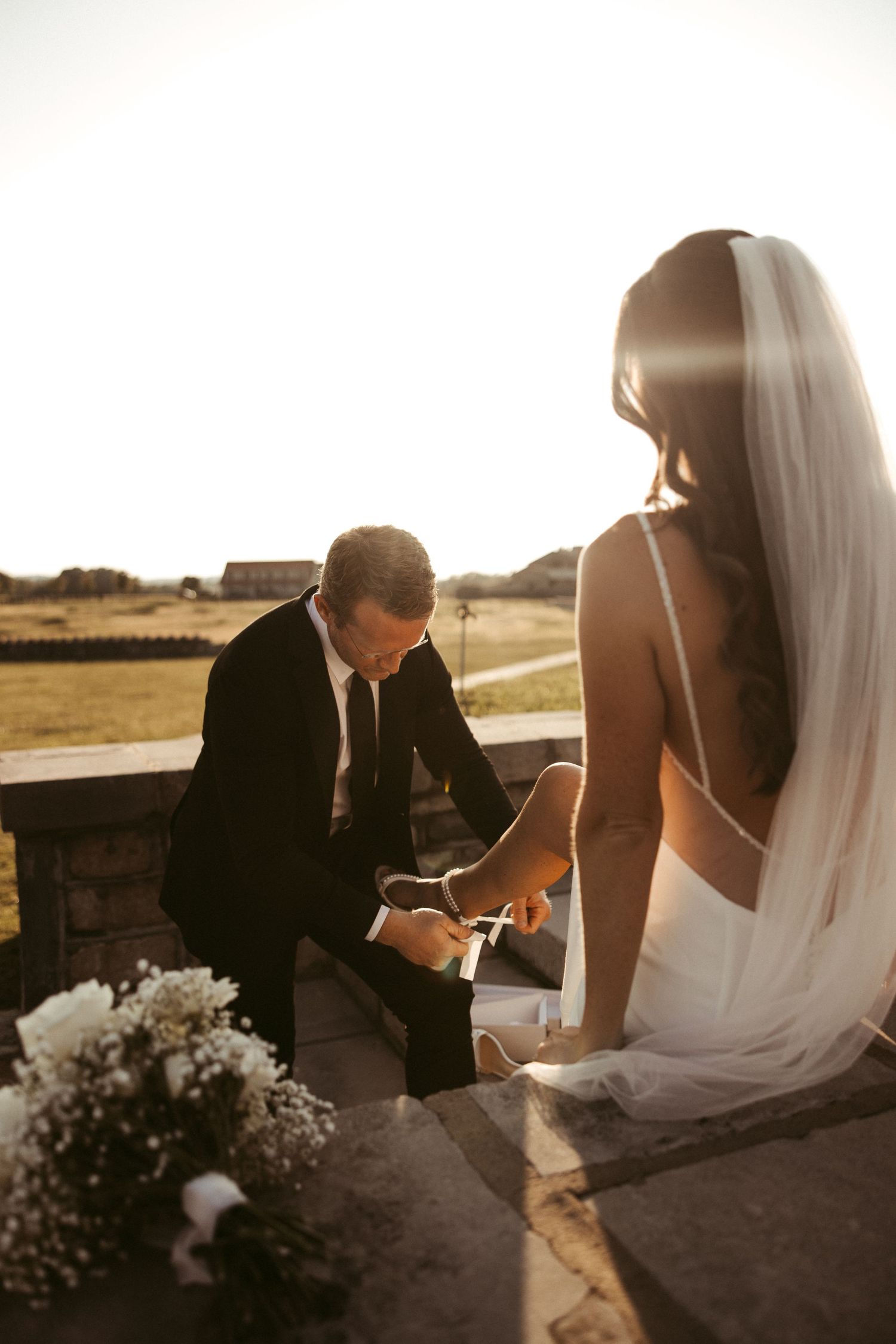 A couple shares an intimate moment on their wedding day at sunset, with baby's breath flowers nearby.