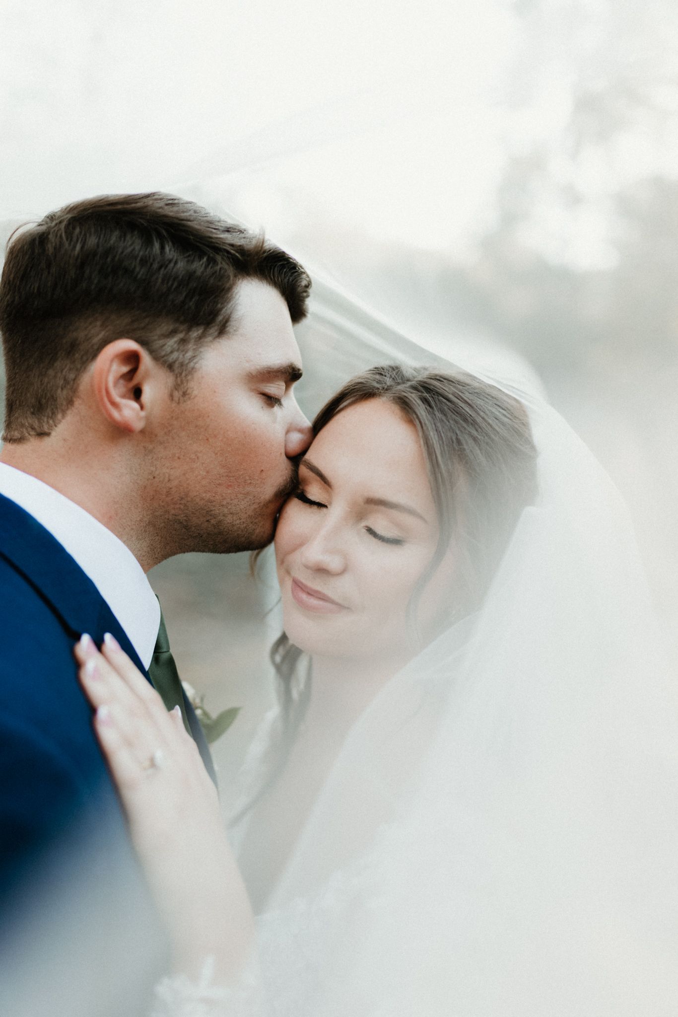 An intimate moment between newlyweds under a delicate veil.